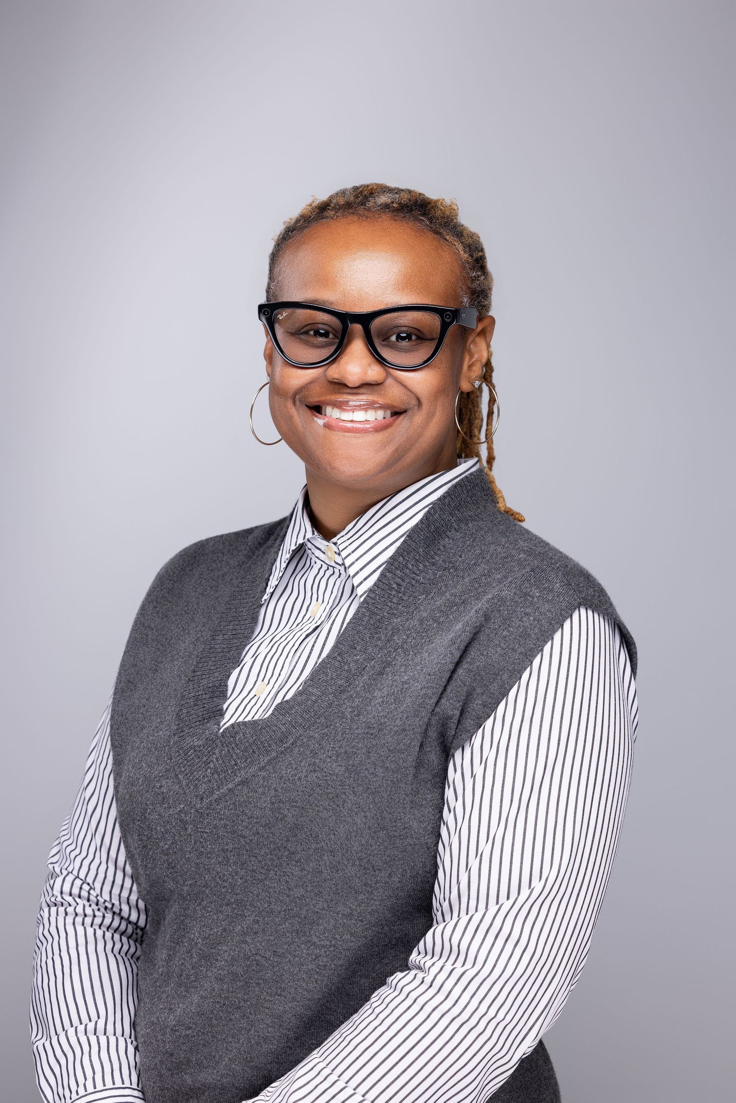 Professional headshots showing a person wearing glasses, a striped shirt and grey vest against a light background.
