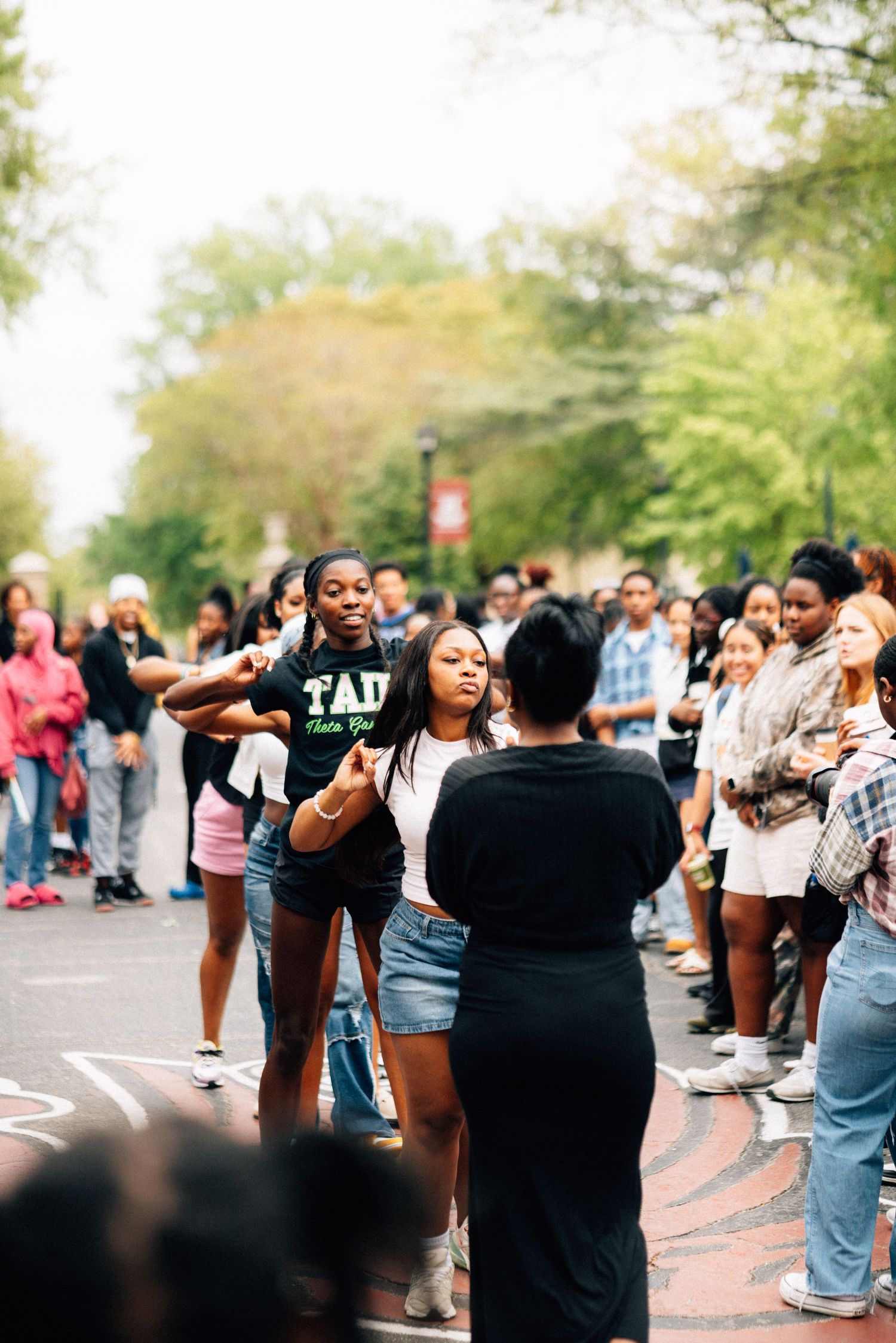 A crowd of Akas gathers outdoors on a college campus during a social event or gathering.