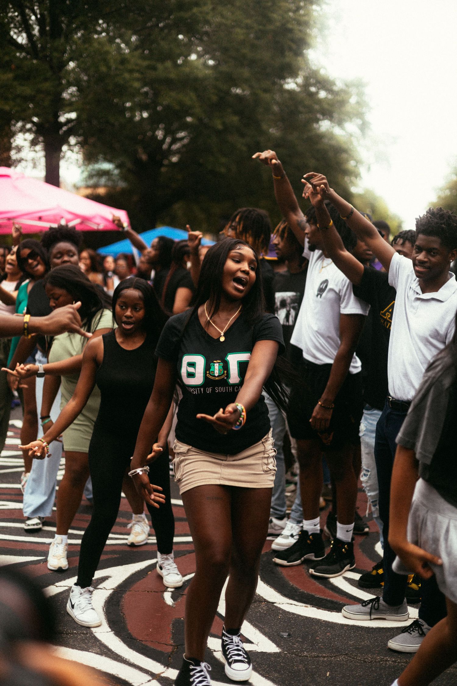 A group of AKA'x dancing and enjoying a lively outdoor celebration or street festival with umbrellas in the background. USC Hip Hop Wednesda