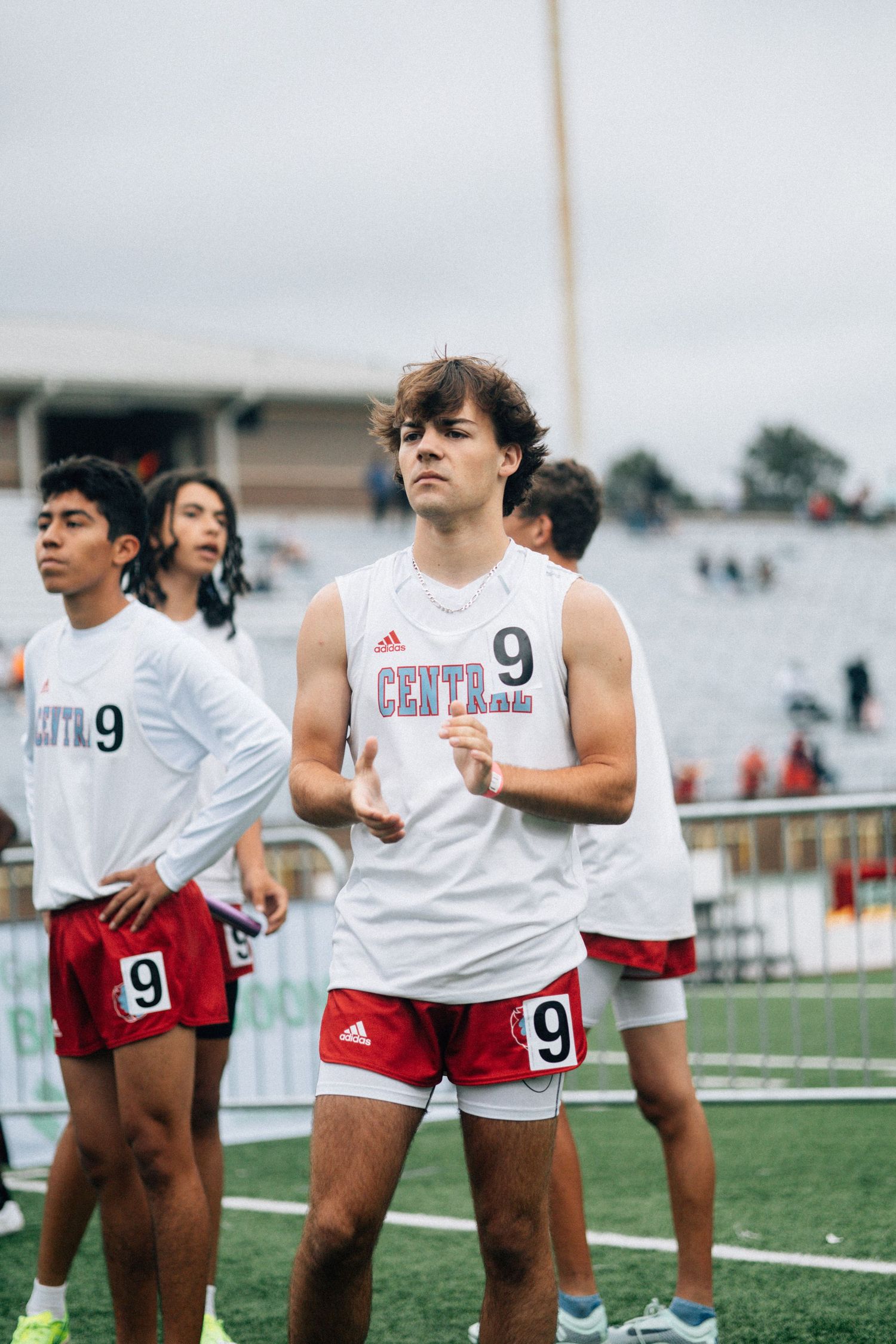 Athletes in white jerseys with number 9 stand on sports field during practice.