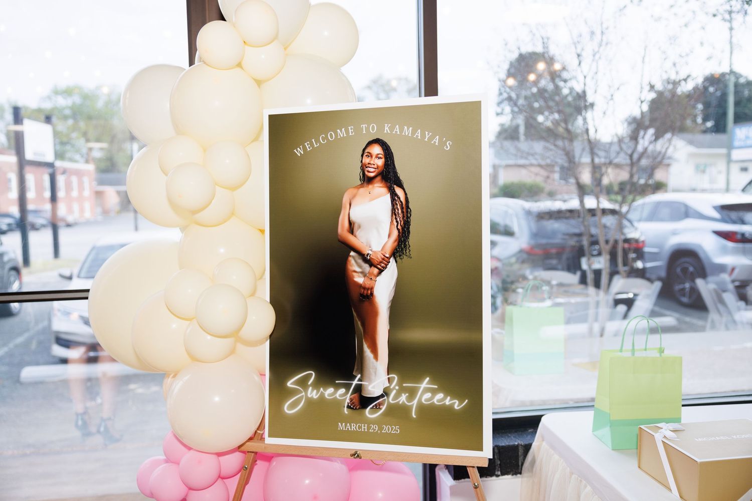 Sweet sixteen welcome sign with balloons and a photo of the birthday girl at an elegant party venue.