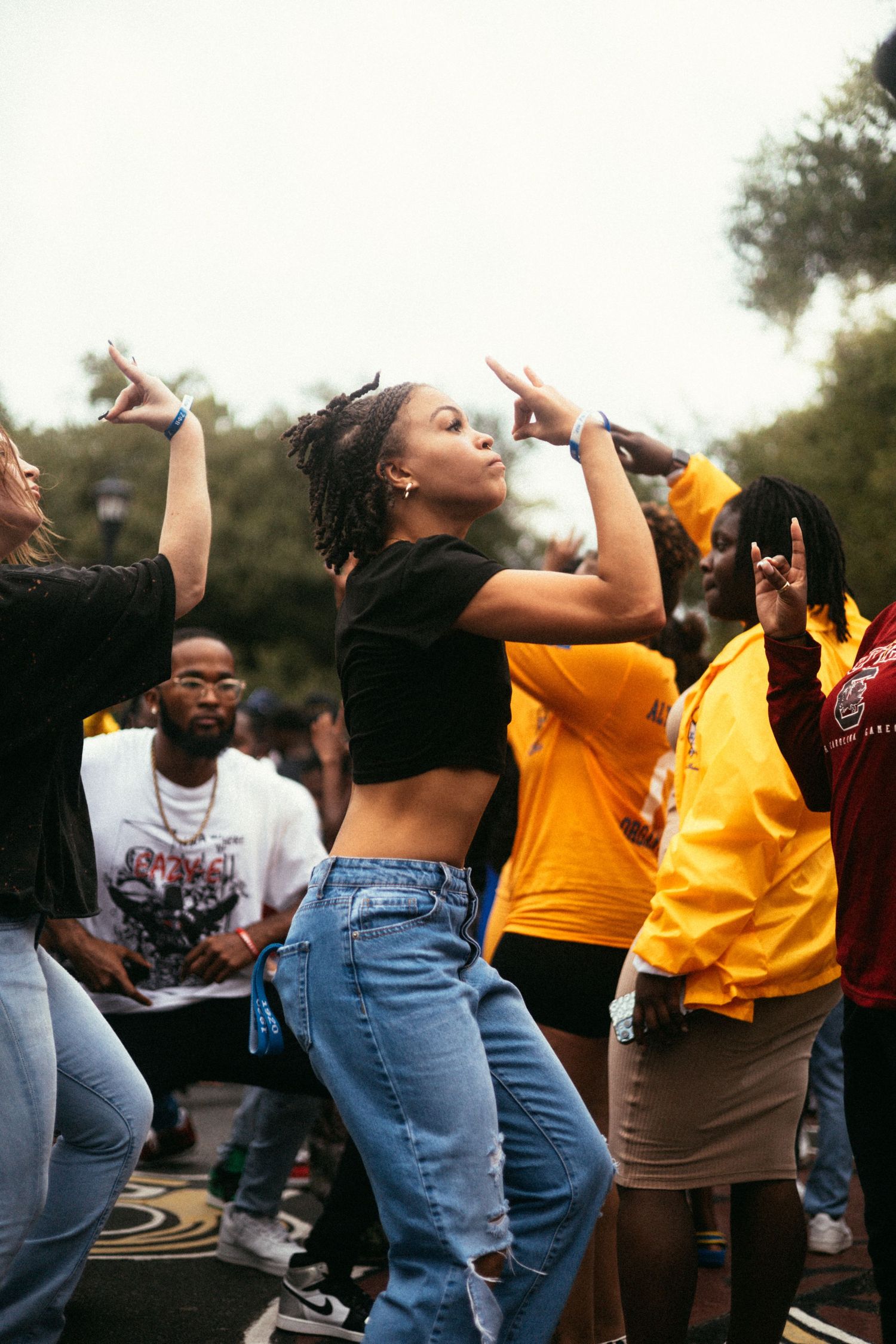 Zetas dancing and enjoying themselves at an outdoor event with someone wearing a black crop top and jeans in focus.