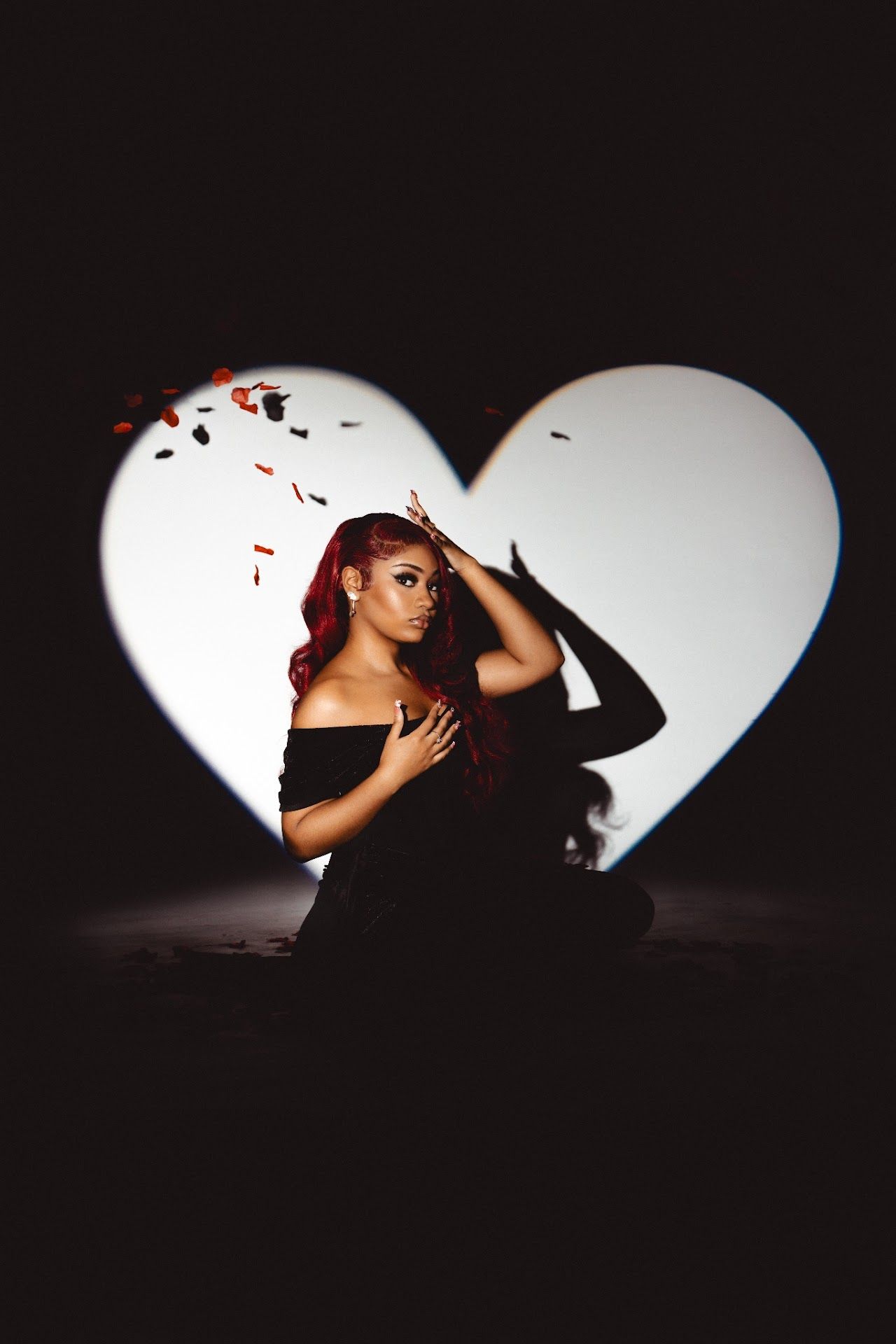 Artistic silhouette portrait framed within a heart shape against dark background showing dramatic lighting and stylized pose.