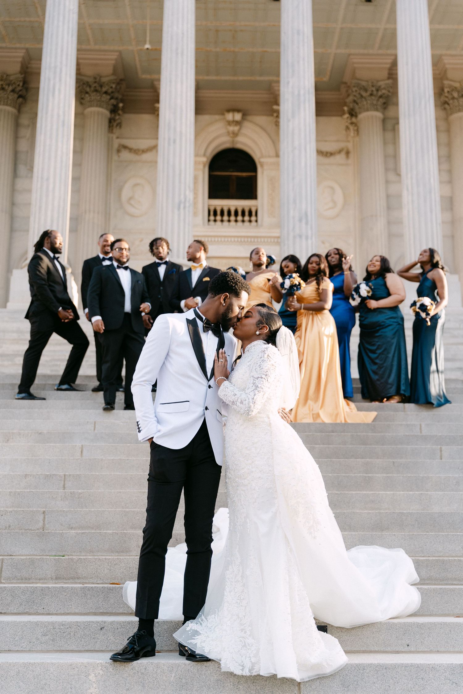 Wedding party poses on grand marble steps with white columns of a courthouse or government building.