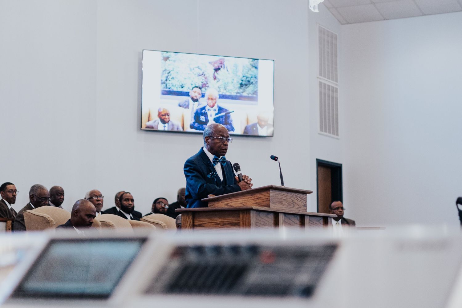 Business professionals gathered in a modern conference room with screens and laptops for a corporate meeting.