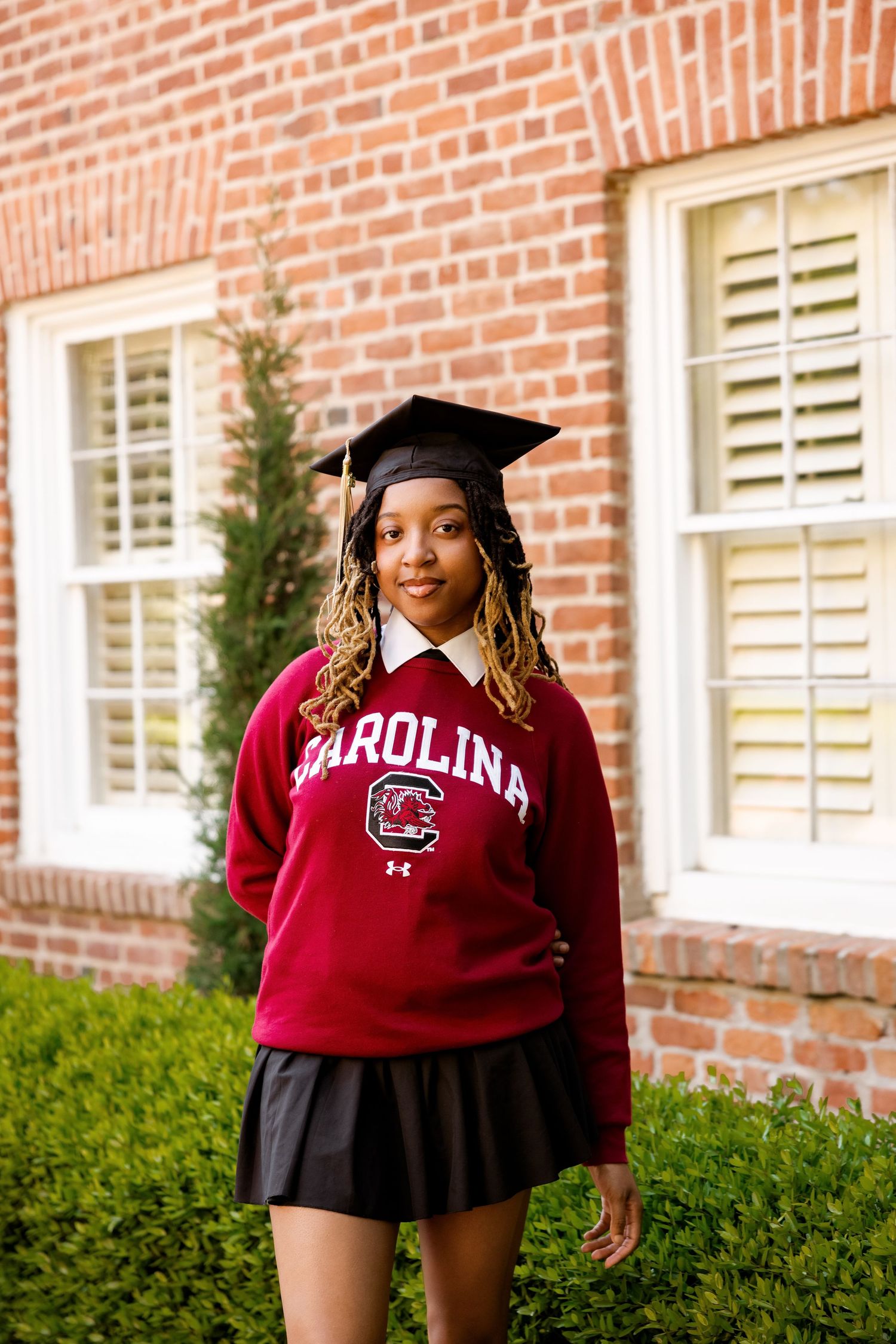 Student in graduation cap celebrates in University of South Carolina gear on campus.