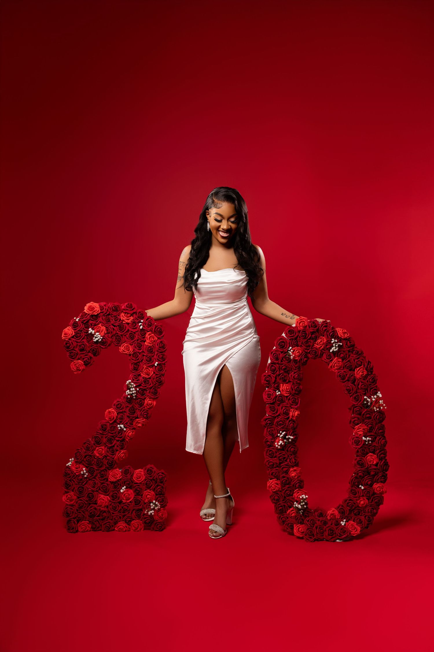 Artistic graduation photos with floral 2020 numbers arranged on red backdrop.