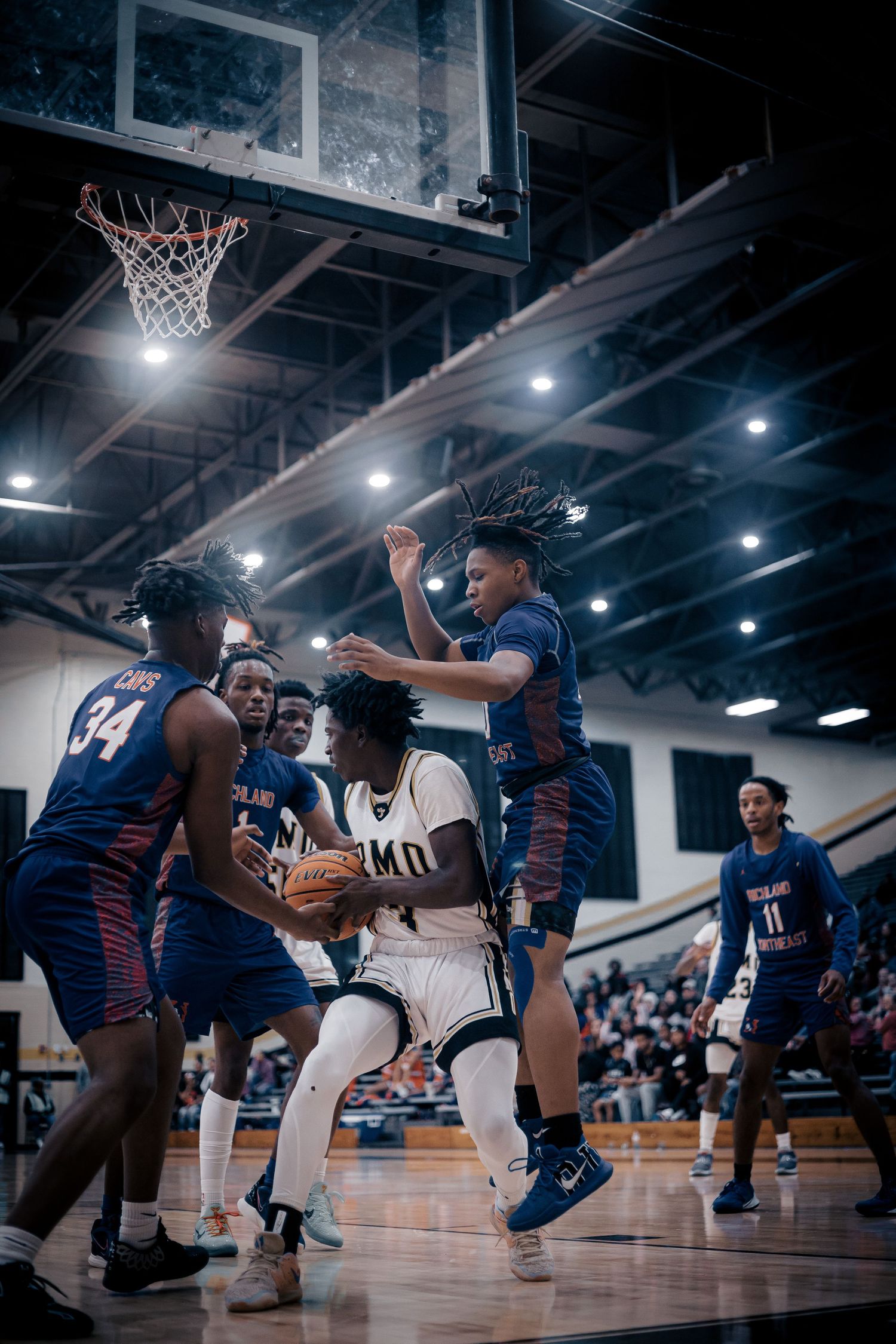 Basketball players from opposing teams compete for position during intense indoor game.