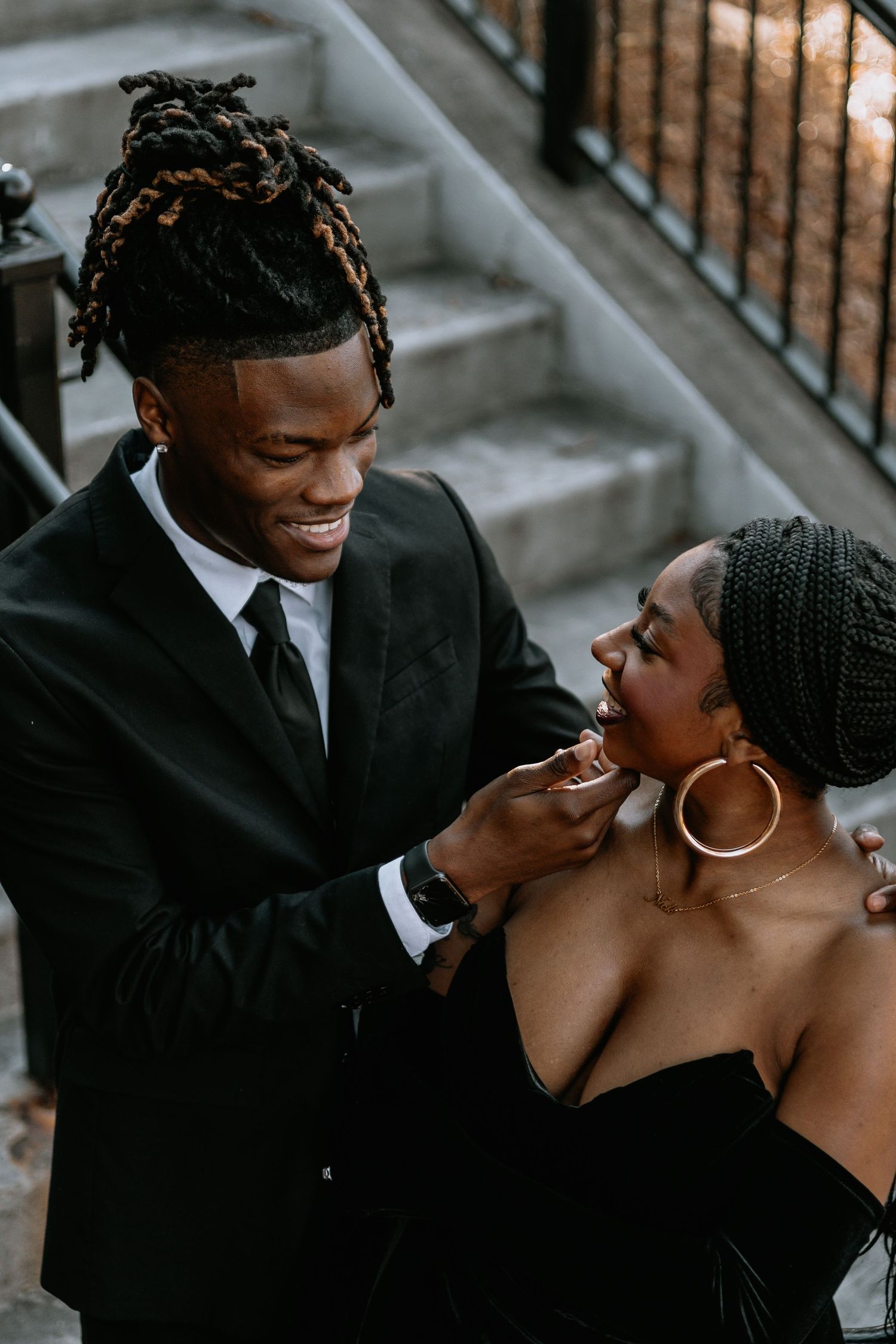 Romantic couple in formal attire sharing an intimate moment on outdoor steps.
