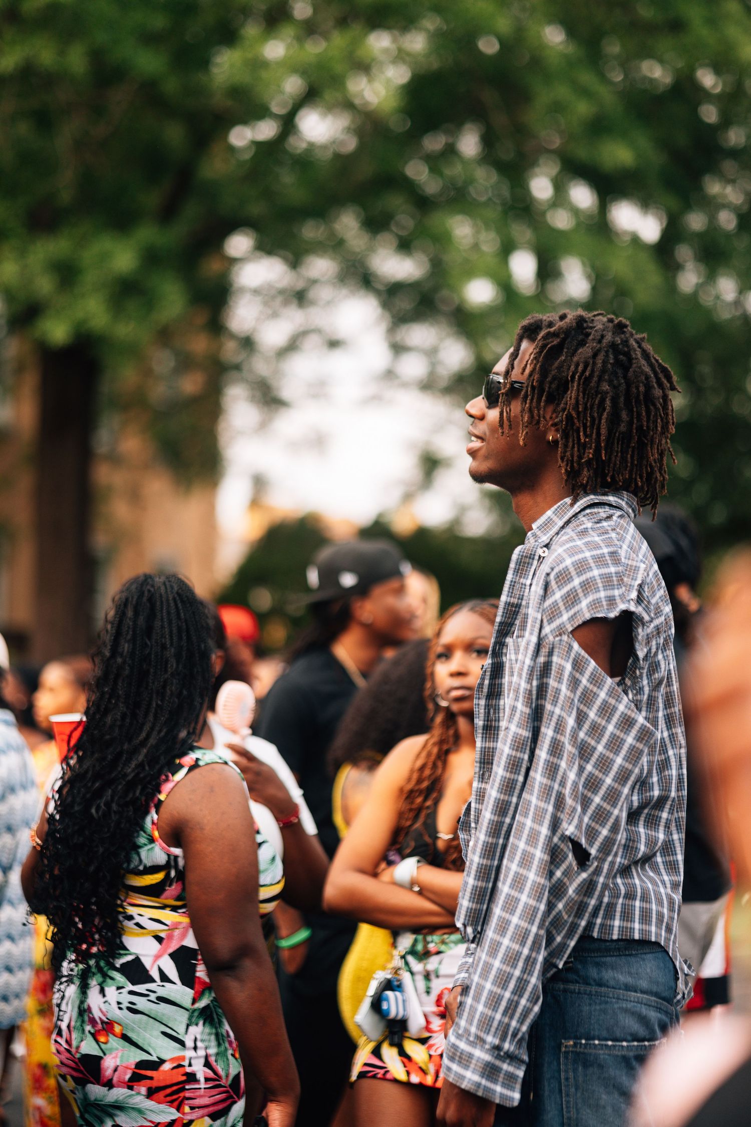 A crowd of festival attendees enjoying an outdoor summer event with blurred trees in the background.