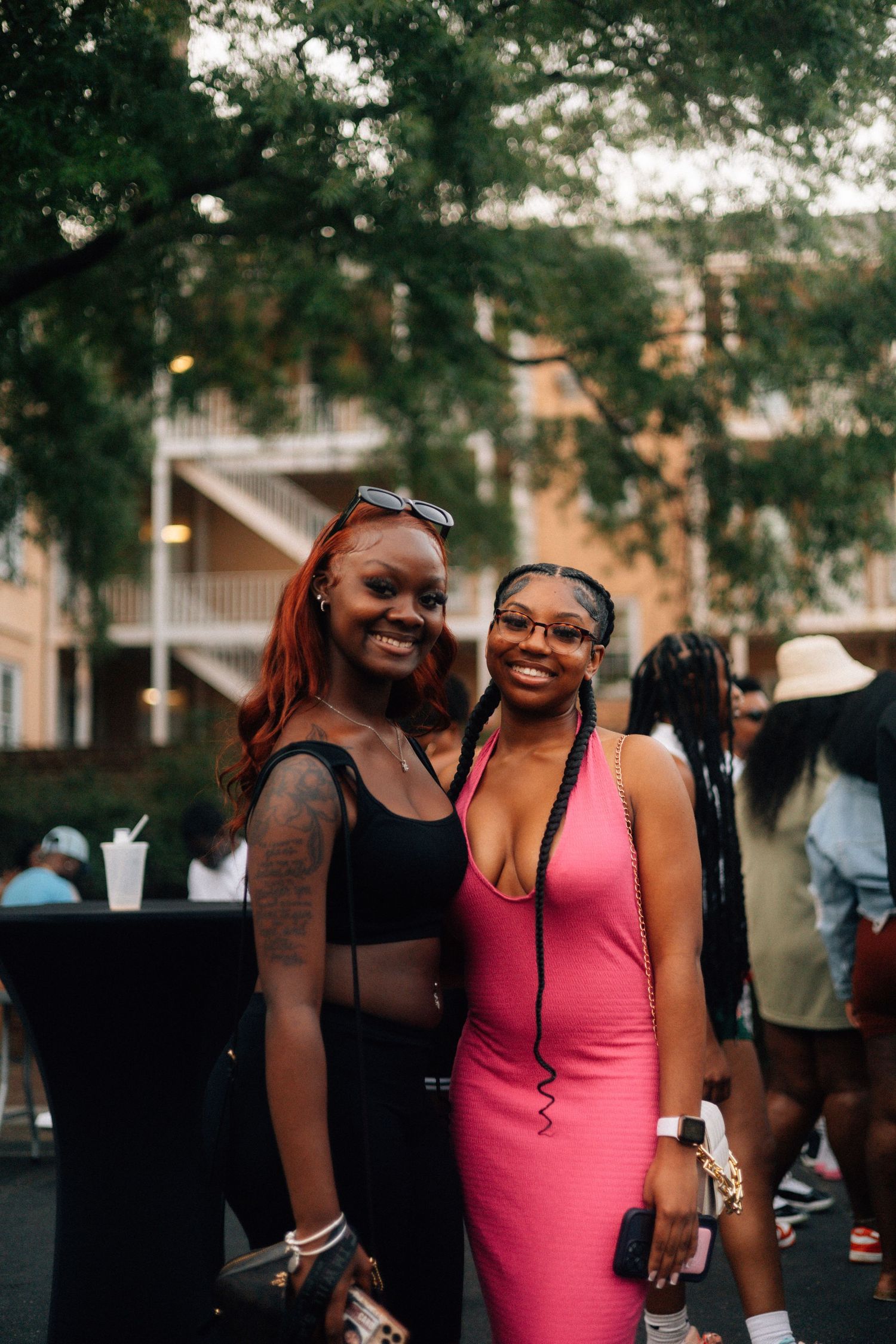 Two friends enjoy a social gathering outdoors, one wearing a black crop top and another in a pink fitted dress. USC Hip Hop Wednesday