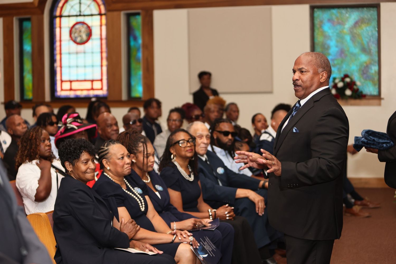 Congregation members worship and sing together during a church service in a sunlit sanctuary.