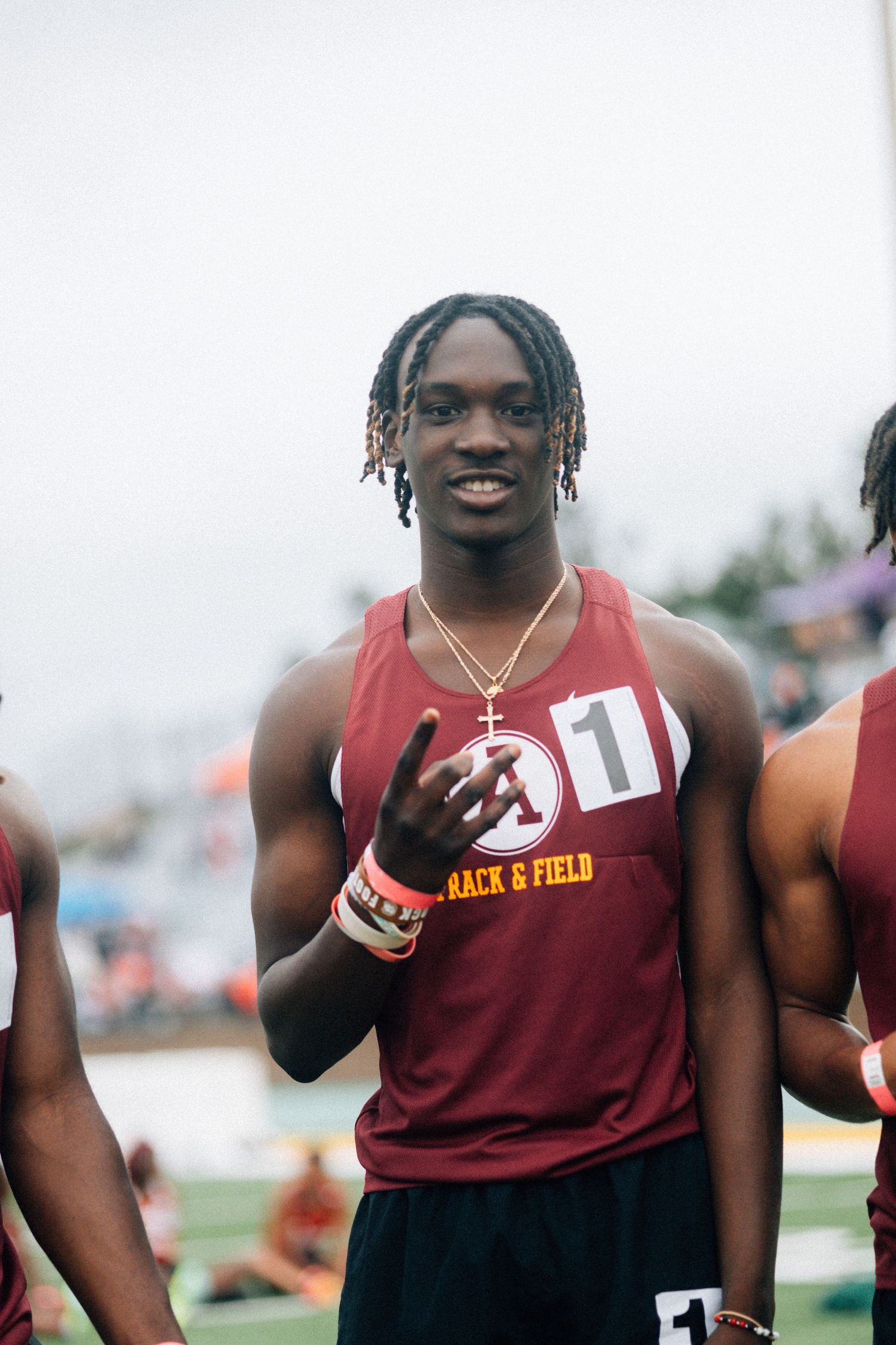 Track and field athletes in maroon uniforms smiling and celebrating at an outdoor event.