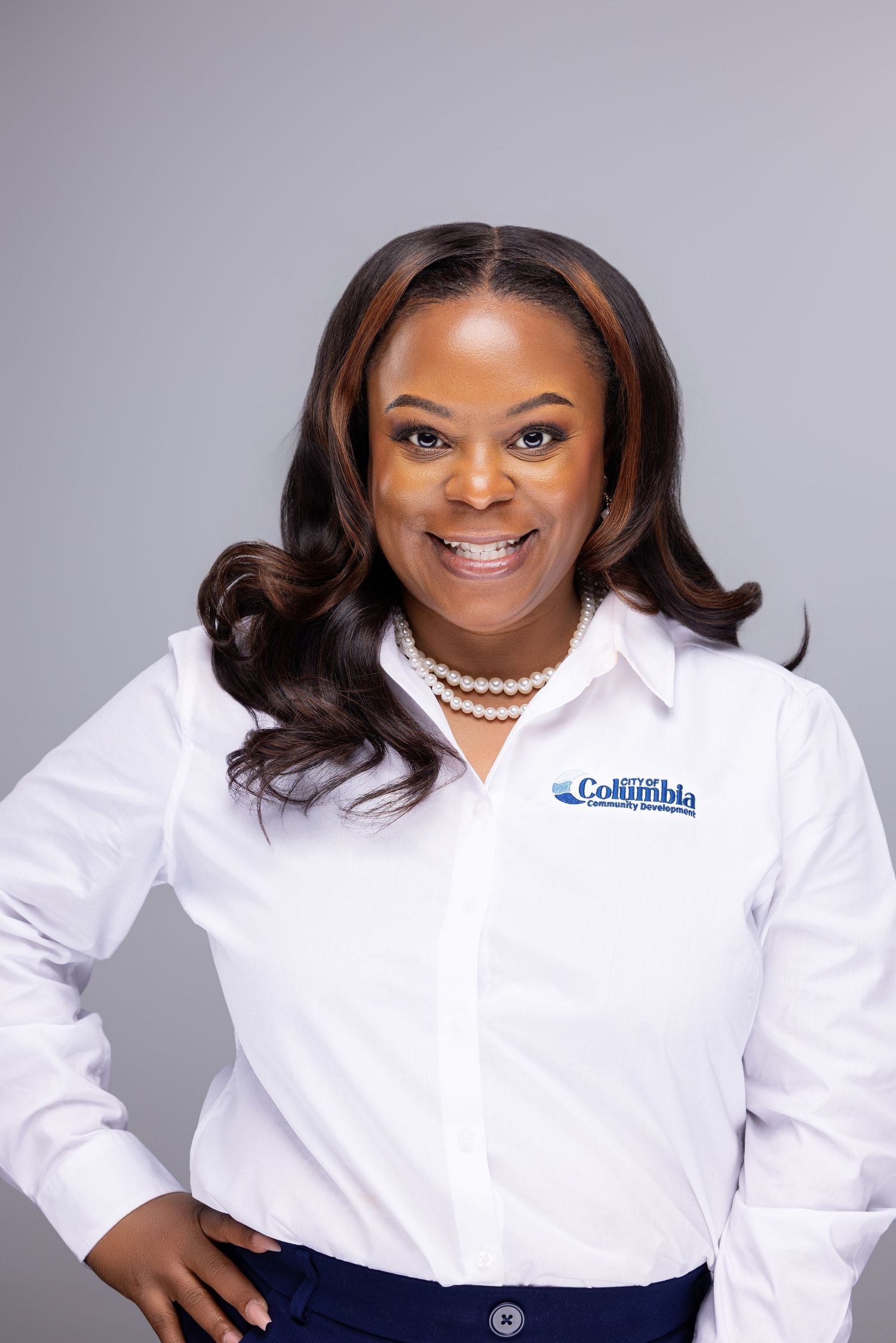 Professional headshot series showing a person wearing a white Columbia branded shirt against a gray background.