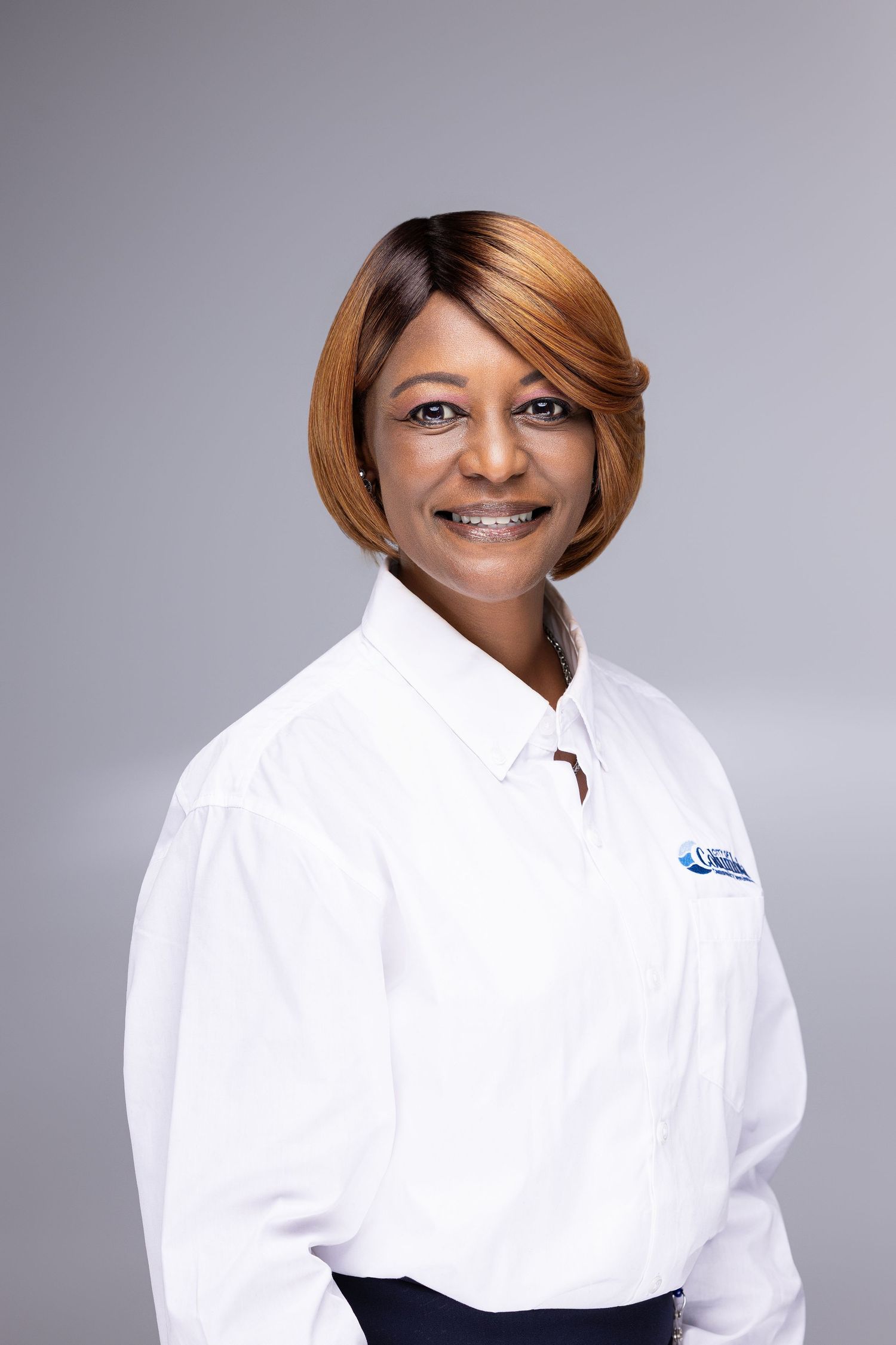 Professional headshot of a person in a crisp white button-down shirt against a gray background.