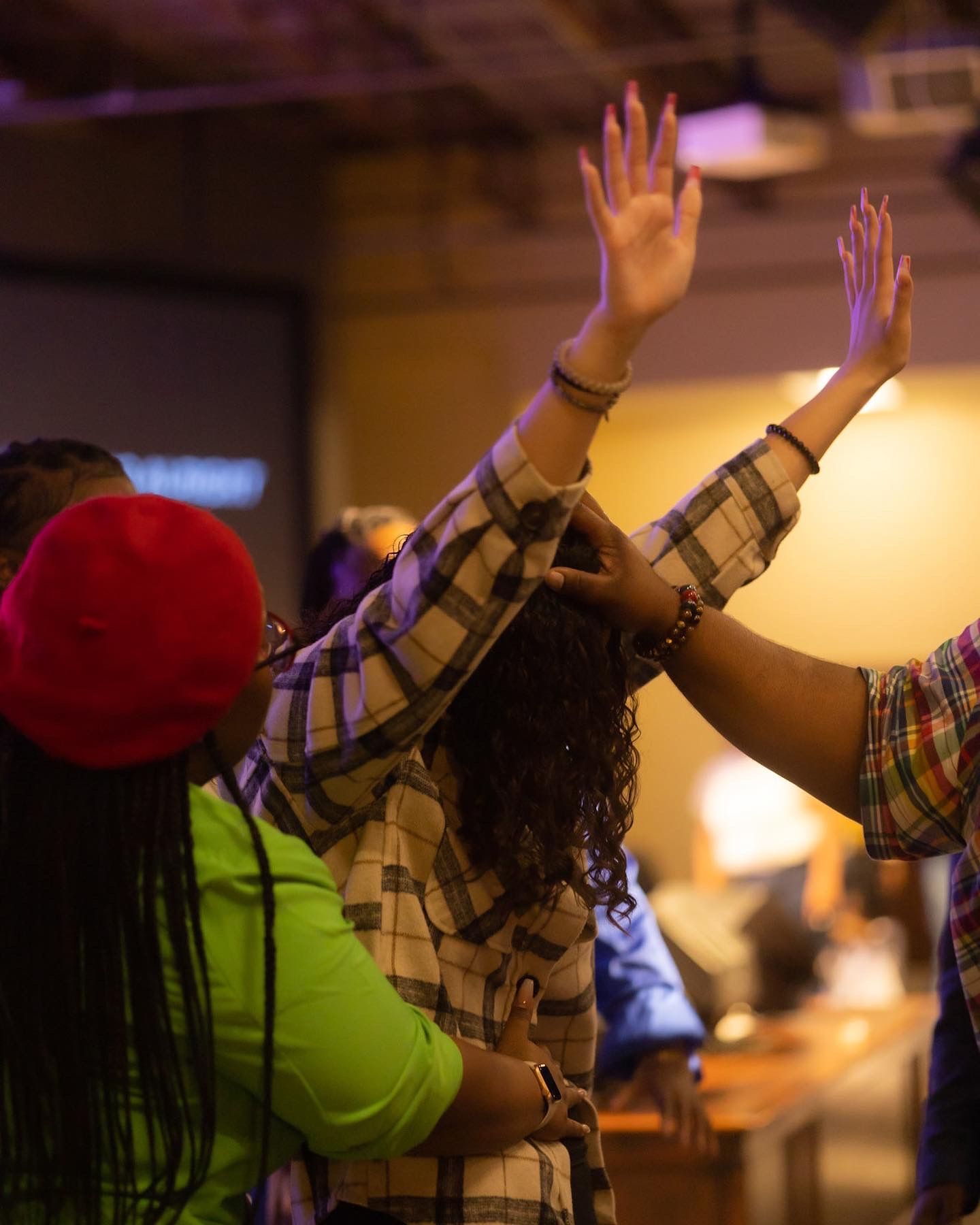People raise their hands in worship during a church service.