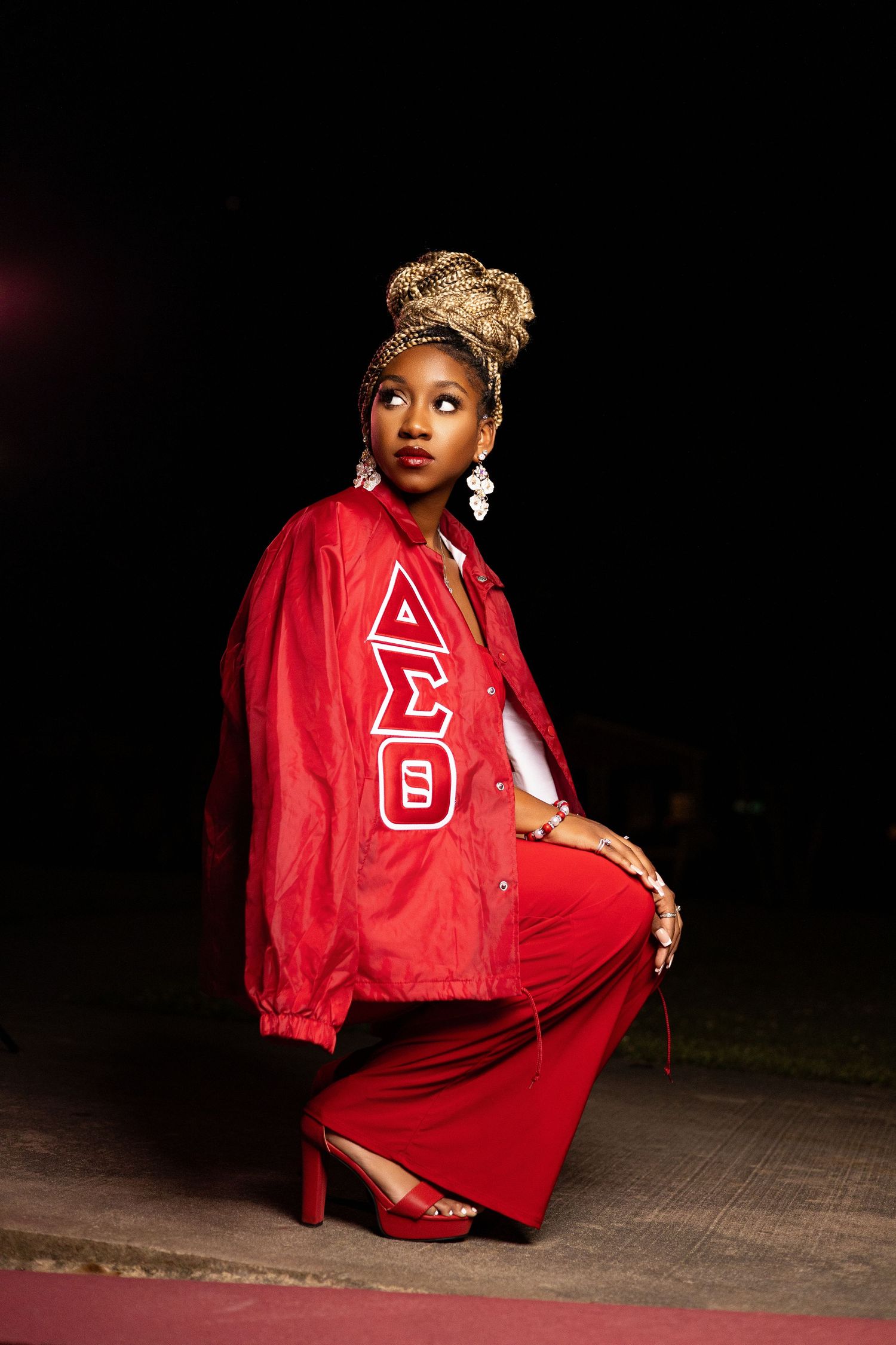 Red letterman jacket and dress ensemble captured in dramatic outdoor lighting.