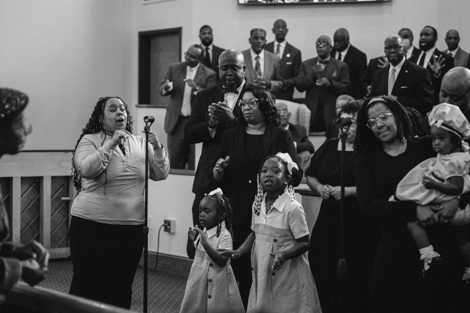 A group of people laugh and smile together during a joyful gathering in black and white.