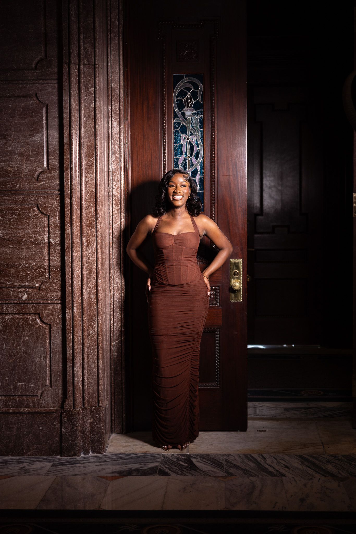 A series of dramatic portraits showing a figure in a brown dress posing against a dark wooden door and brick wall.