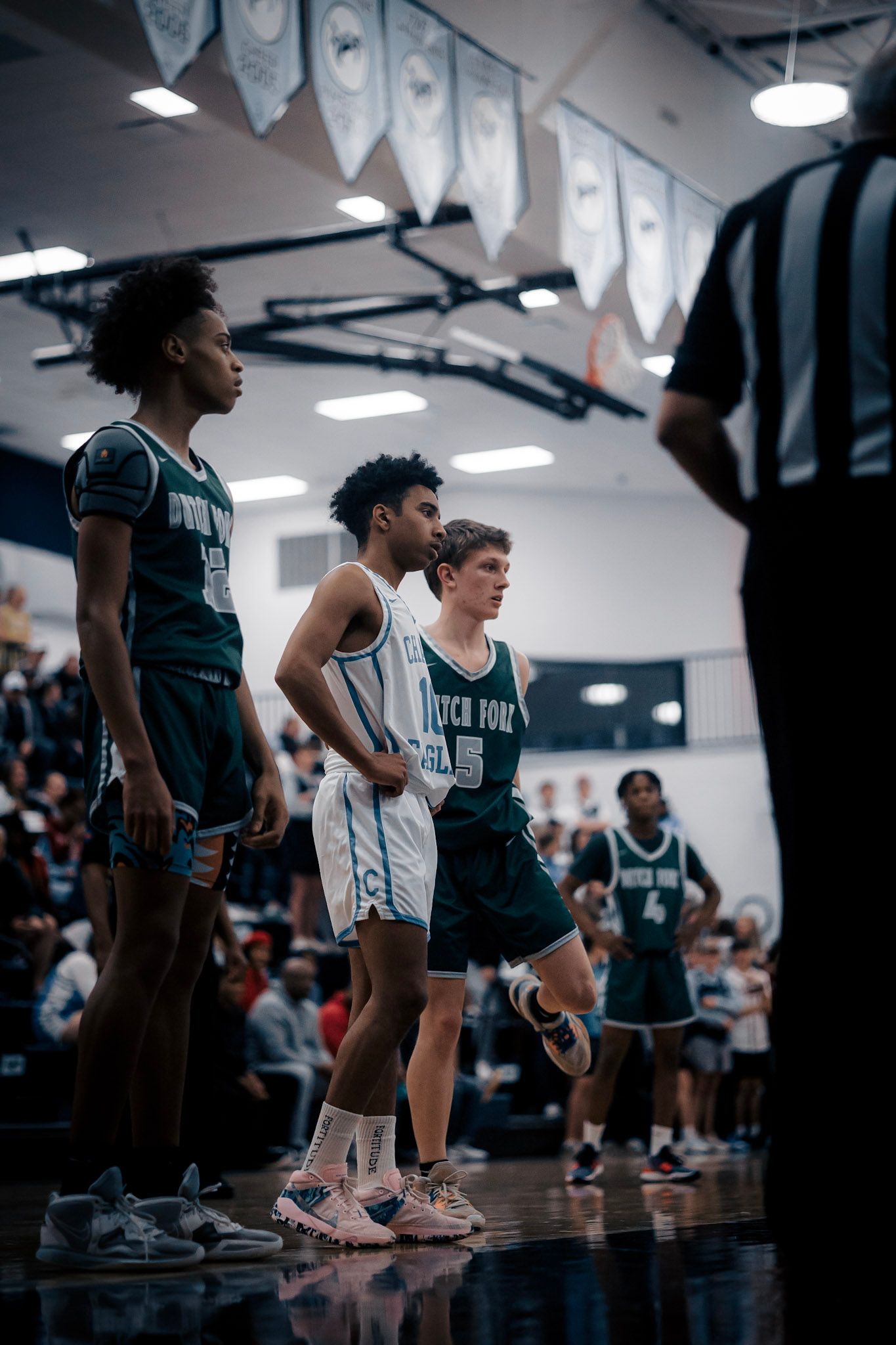 Basketball players line up during game with referee in indoor gymnasium.