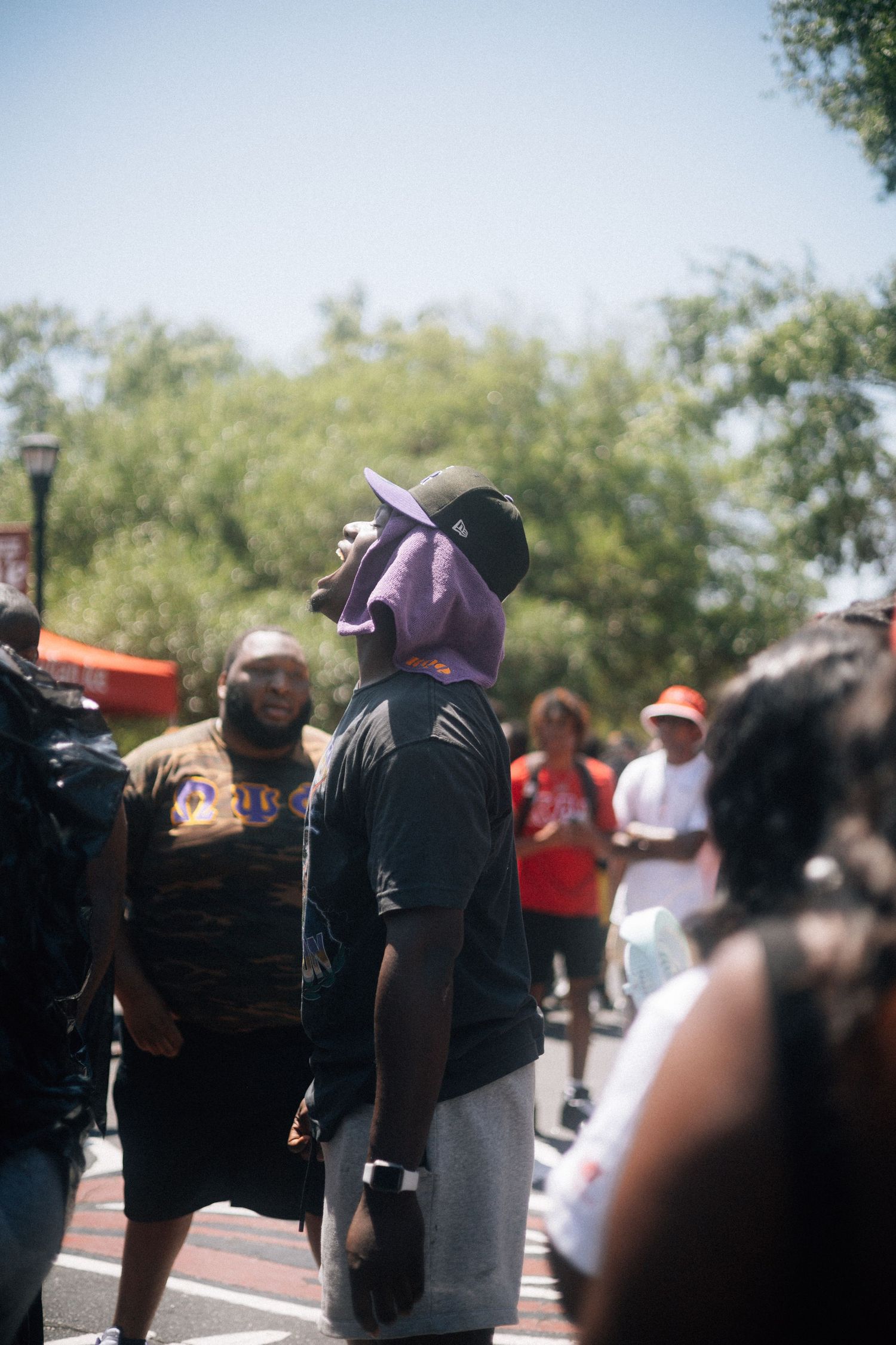 Person wearing a purple bandana and baseball cap stands among a crowd outdoors on a sunny day.  USC Hip Hop Wednesday
