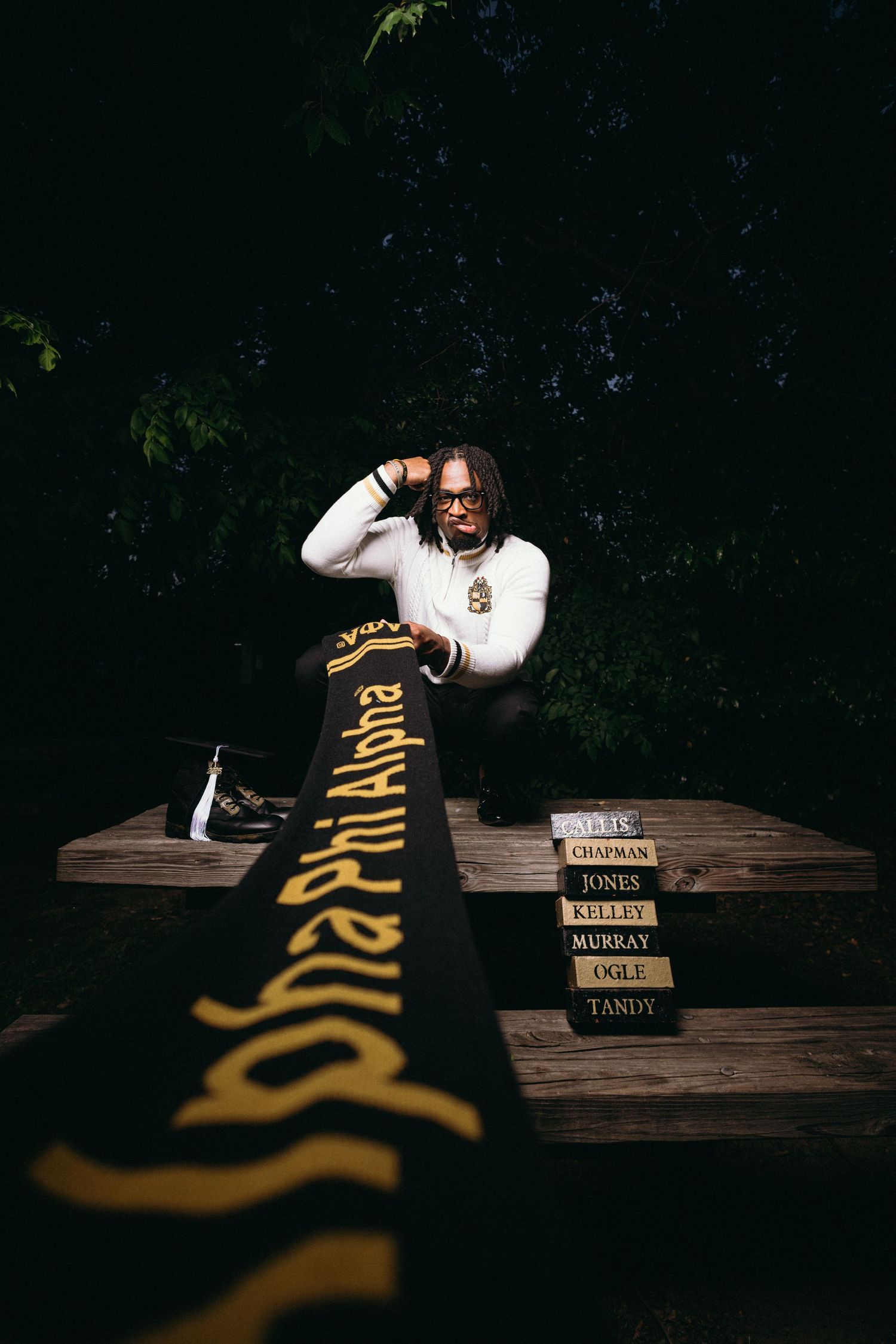 Artistic low-light photo featuring stacked books and Alpha Phi branding.