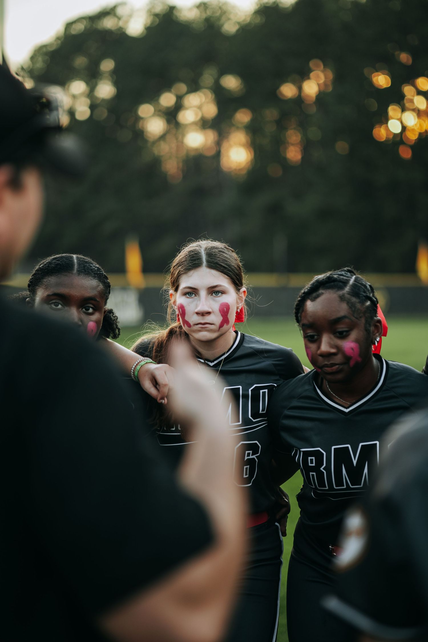 Athletes in team uniforms gather at sunset during an outdoor game or practice.