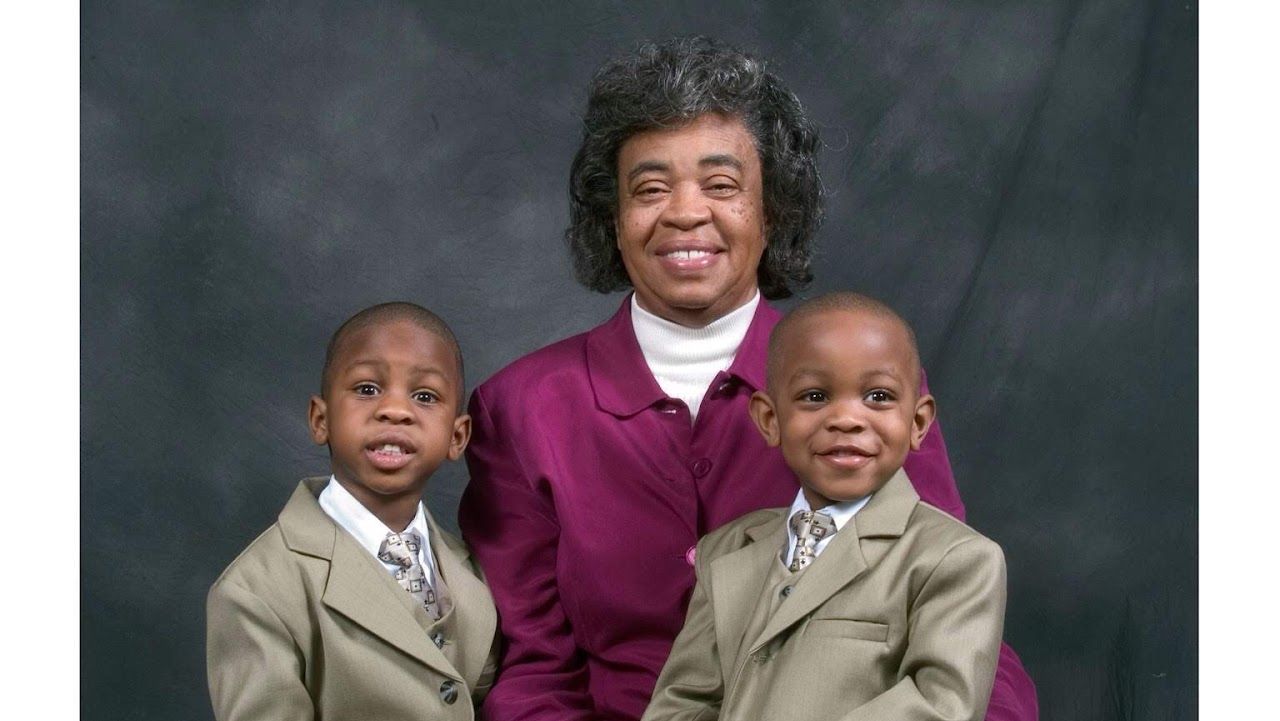 Studio portrait with purple and beige formal attire against dark background.