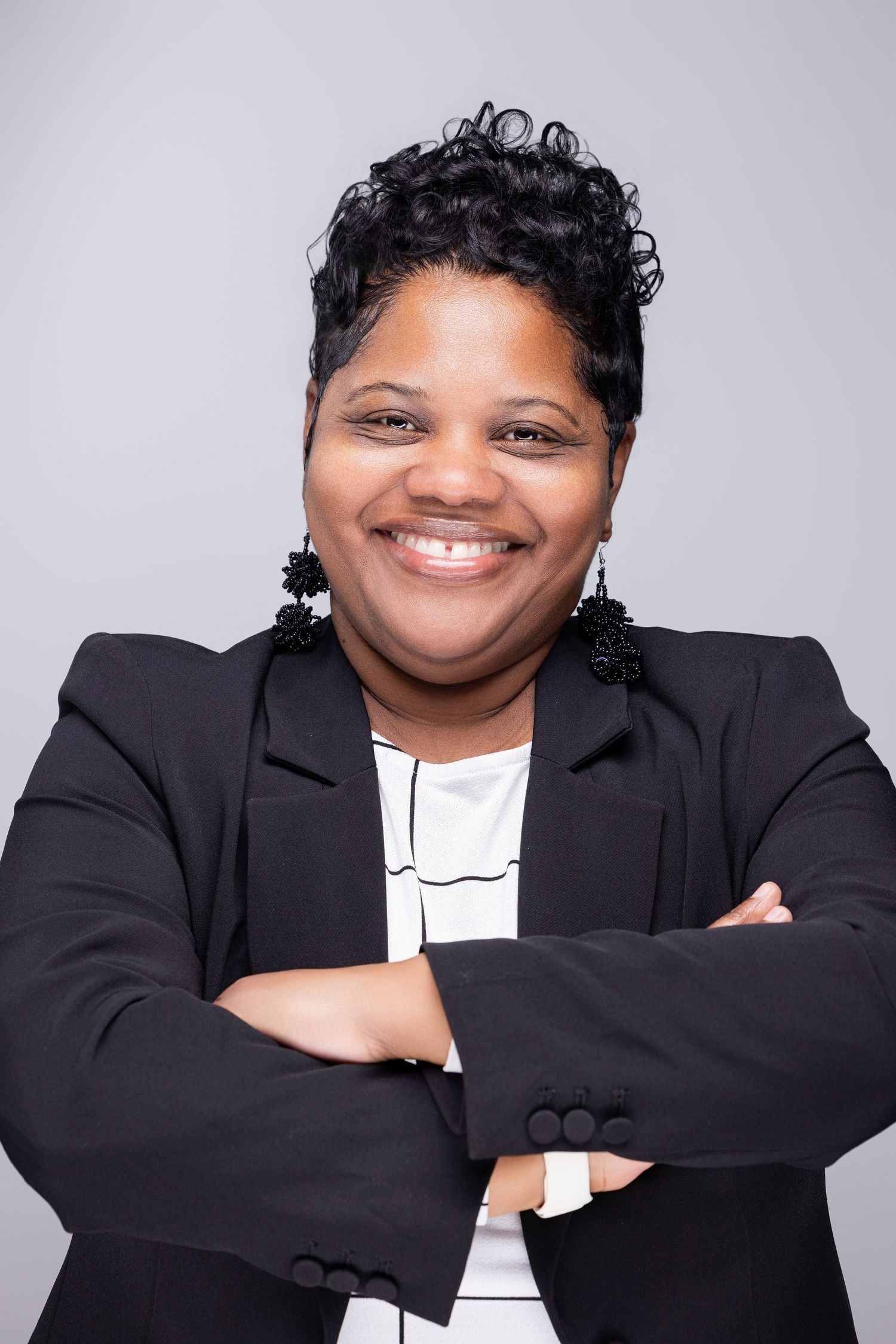 Professional portraits of someone in a black blazer and white top posing expressively against a grey backdrop.