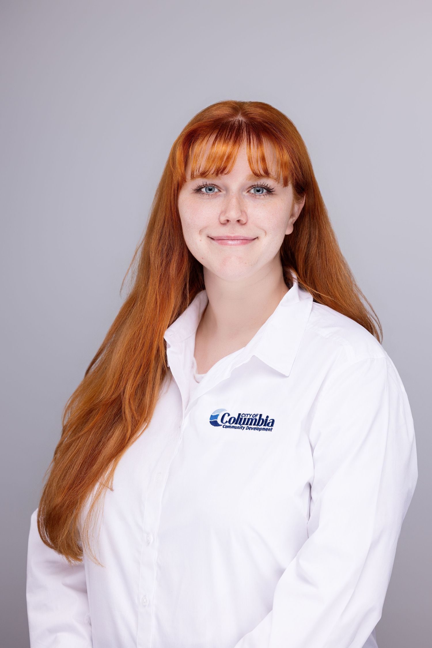 Professional headshot series of a person in a white Columbia branded collared shirt against a gray backdrop.