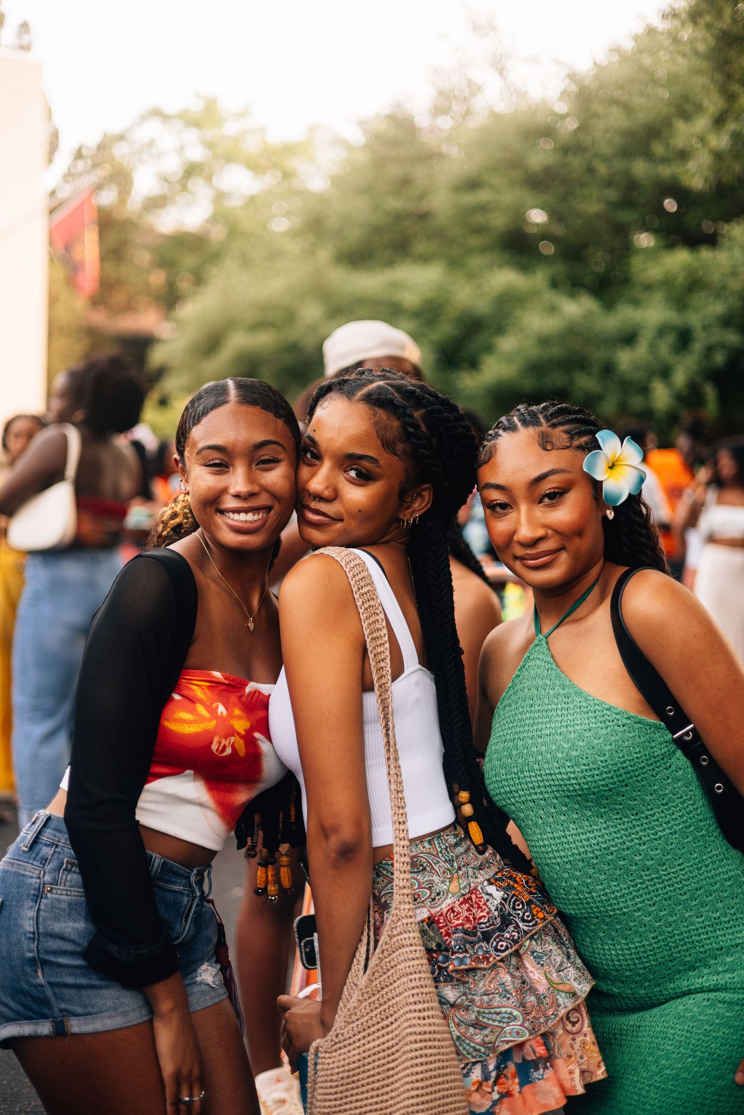 A candid photo of friends enjoying a sunny outdoor festival with tropical flowers and colorful summer outfits.