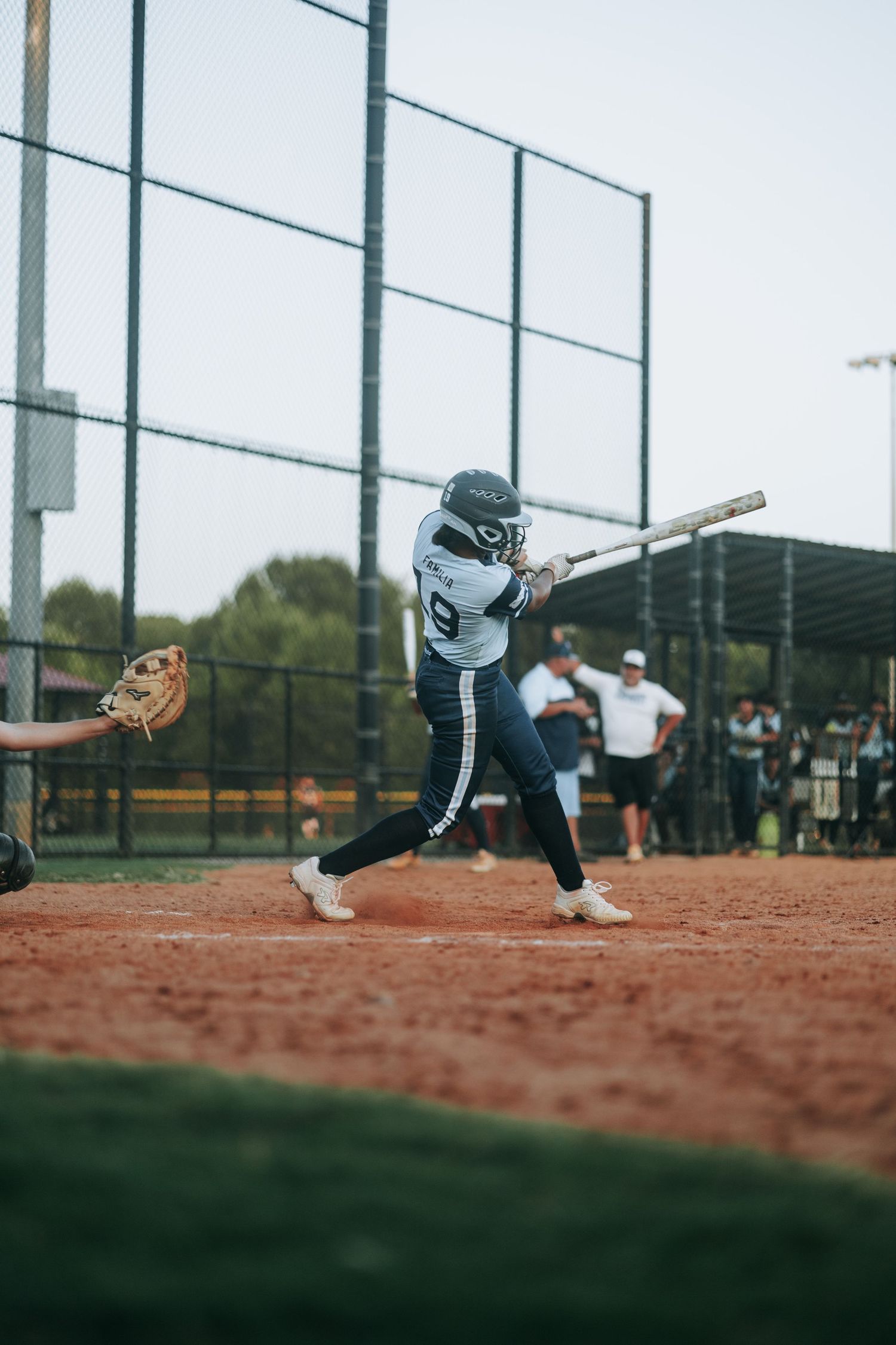 A low angle view of a softball player diving for a ball on the dirt infield.