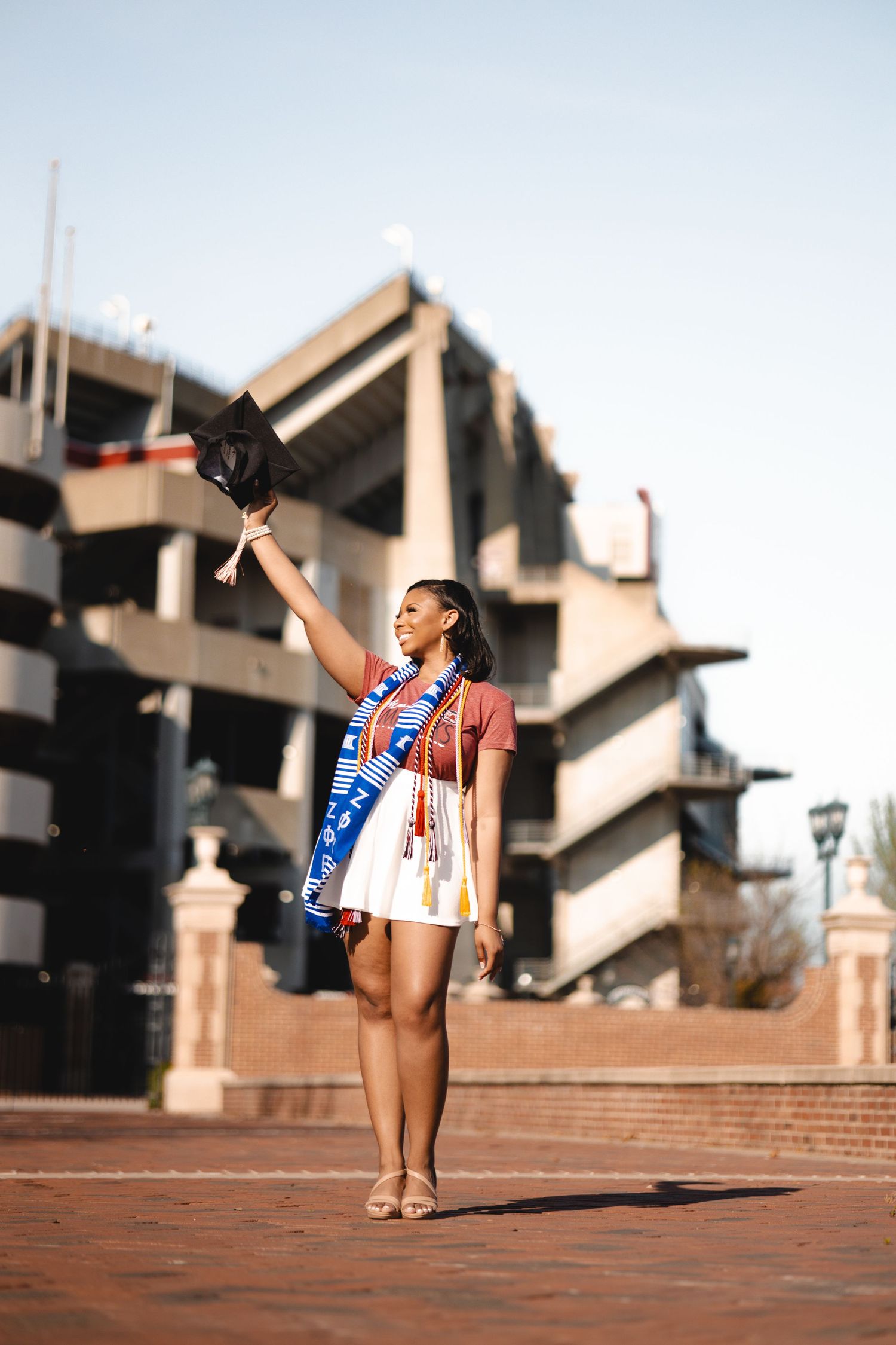 Dynamic graduation photo session with celebratory poses on brick steps near campus architecture.