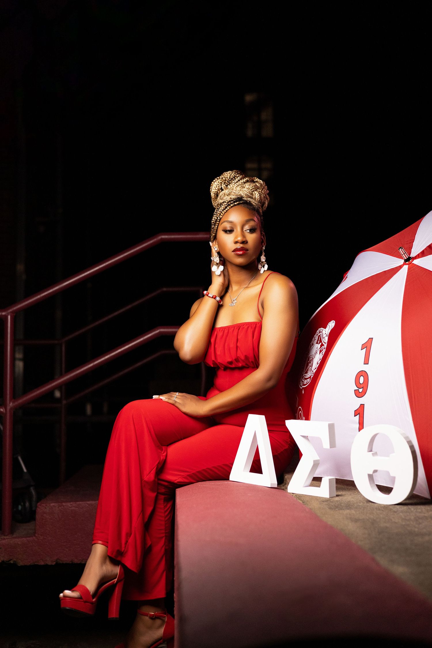 Dramatic portrait session with red dress against large white numbers in low-key lighting.