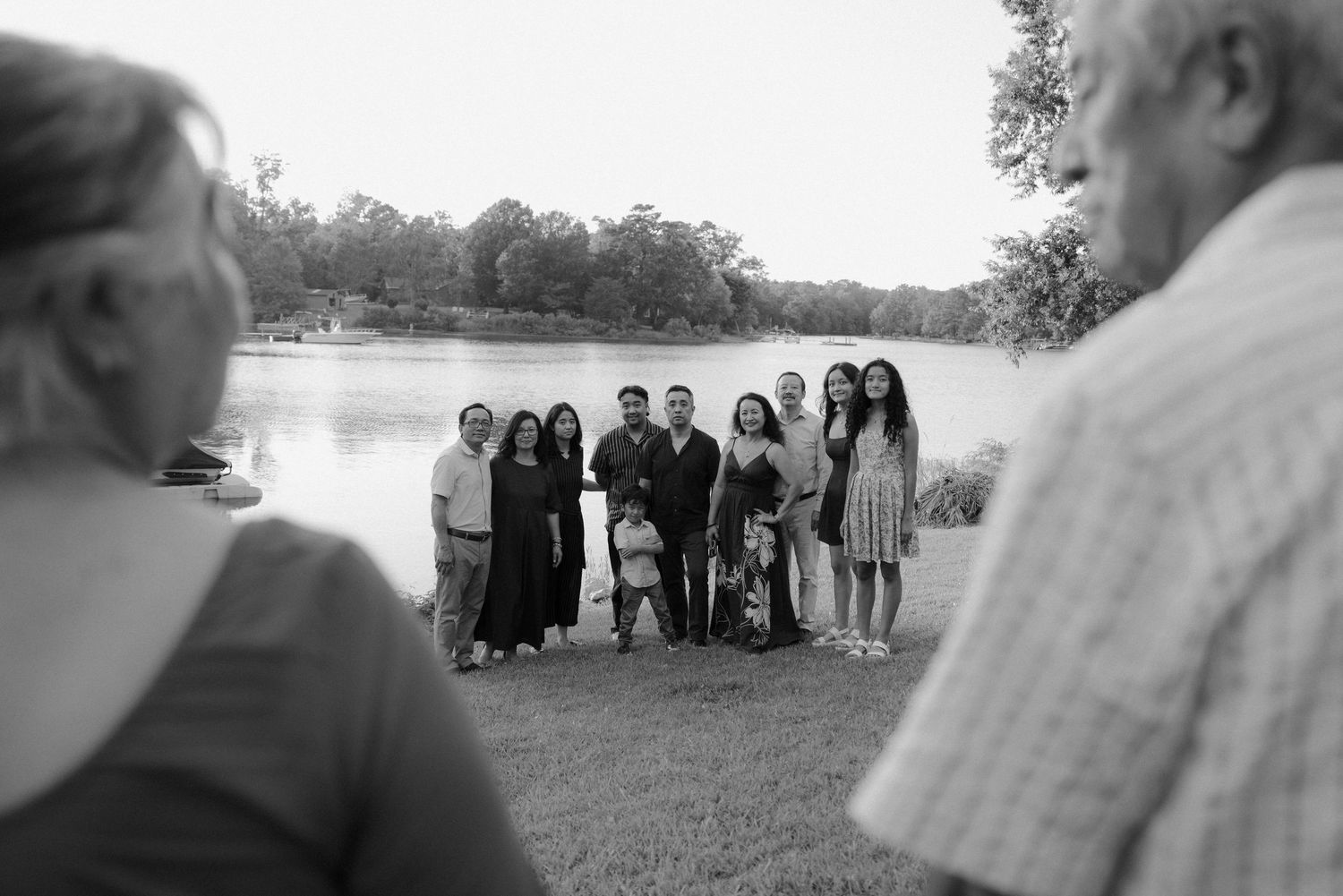Group of people gathered by a lake for a family photo in black and white.