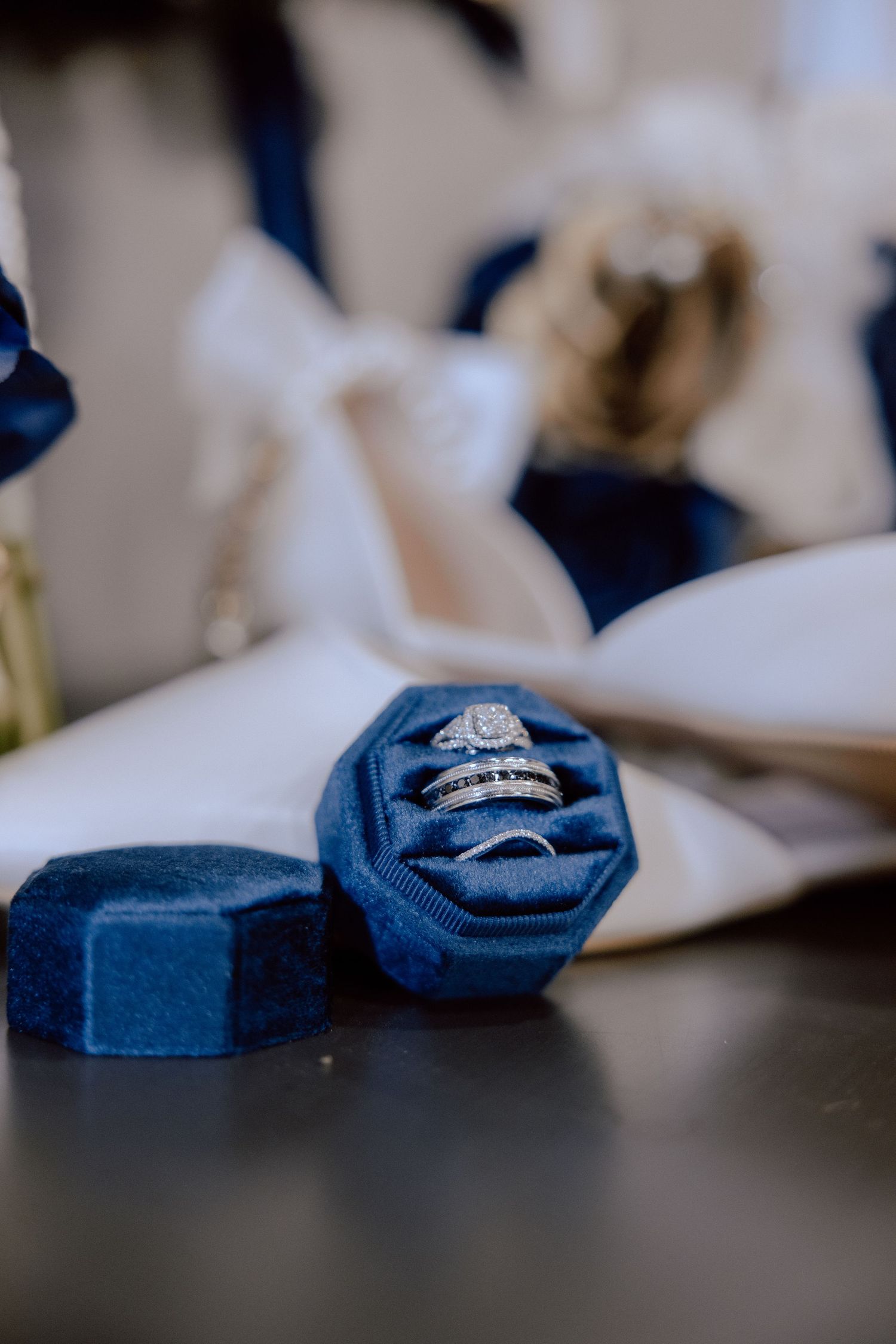 Diamond engagement ring sits on a navy blue velvet ring box shown from different angles in a collage.