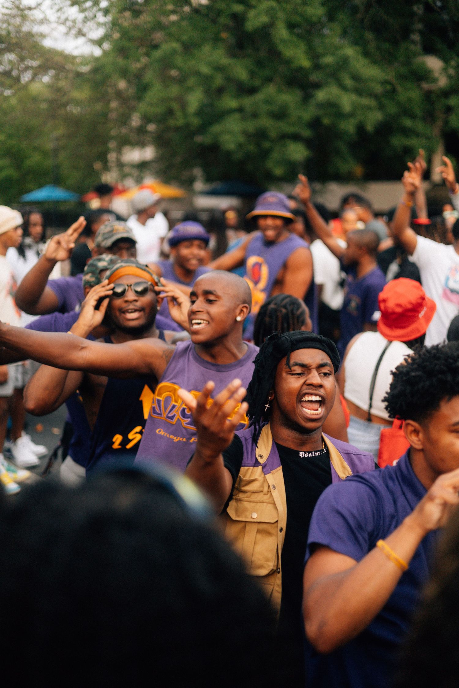 A crowd of QUES at an outdoor event expressing joyful emotions with raised hands and animated expressions. USC Hip Hop Wednesday