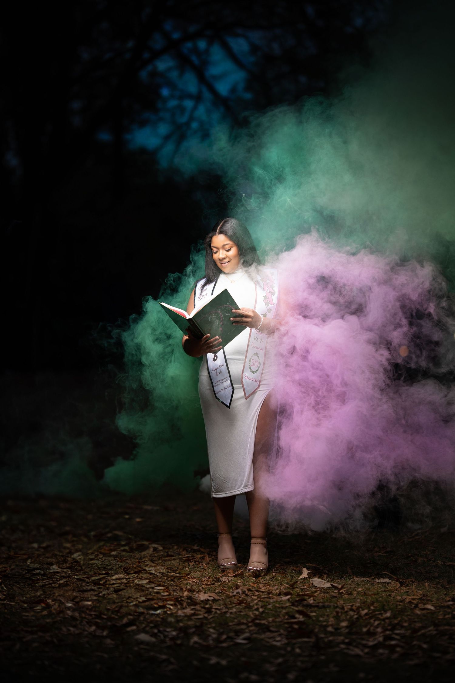 A person stands in a dramatic cloud of pink and teal smoke during a creative outdoor photo shoot.