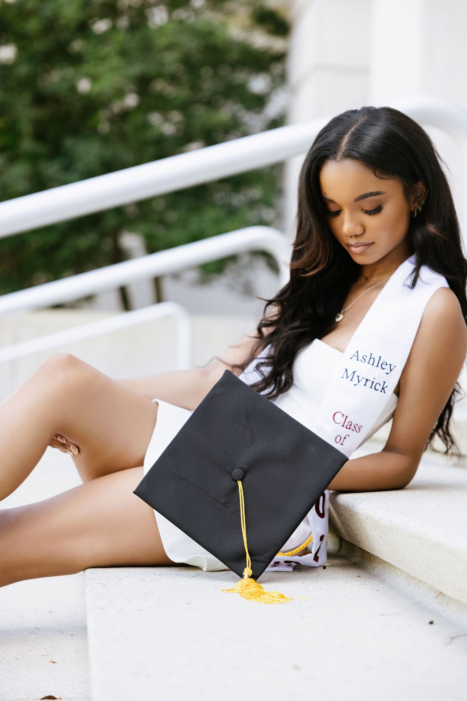 A series of photos showing someone signing a graduation cap while laying on a white surface.