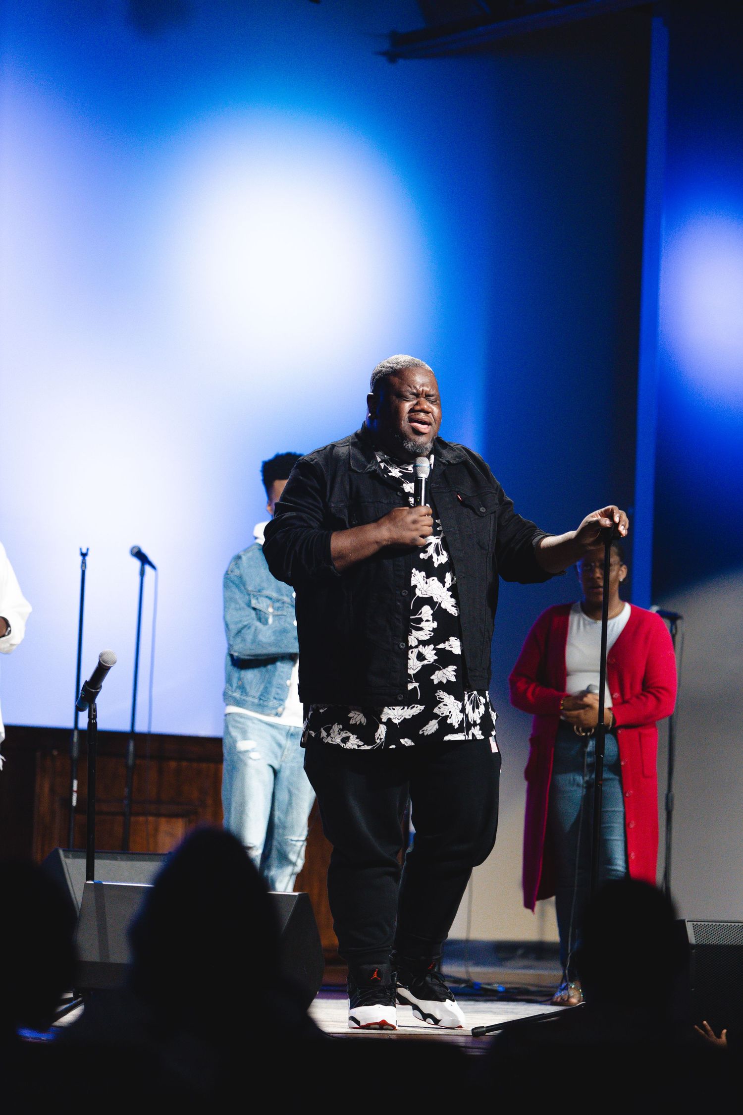 Passionate gospel performance on stage with blue lighting and backup singers.