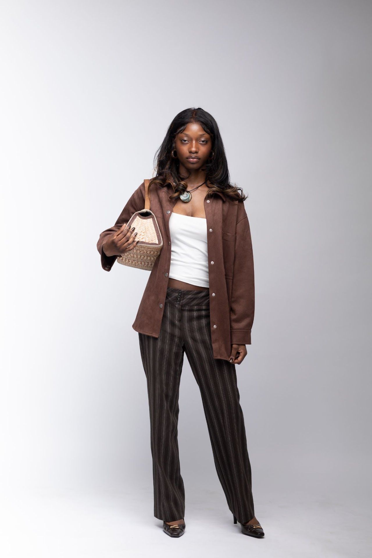 Three fashion photos of a model wearing brown corduroy pants, a white top, and an oversized brown jacket against a gray backdrop.