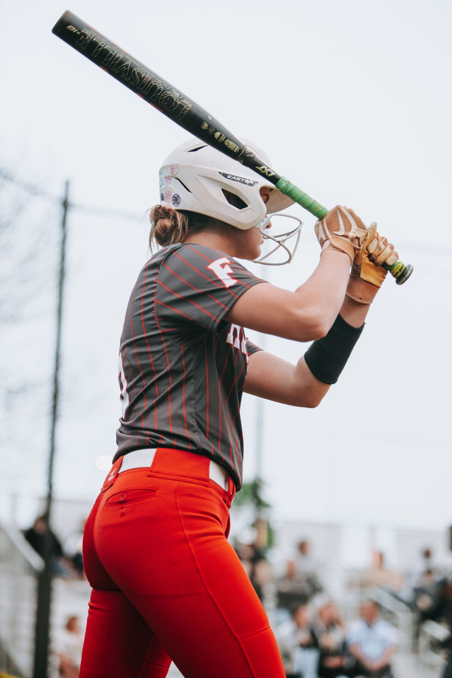 Baseball player in red uniform practicing batting stance during game.
