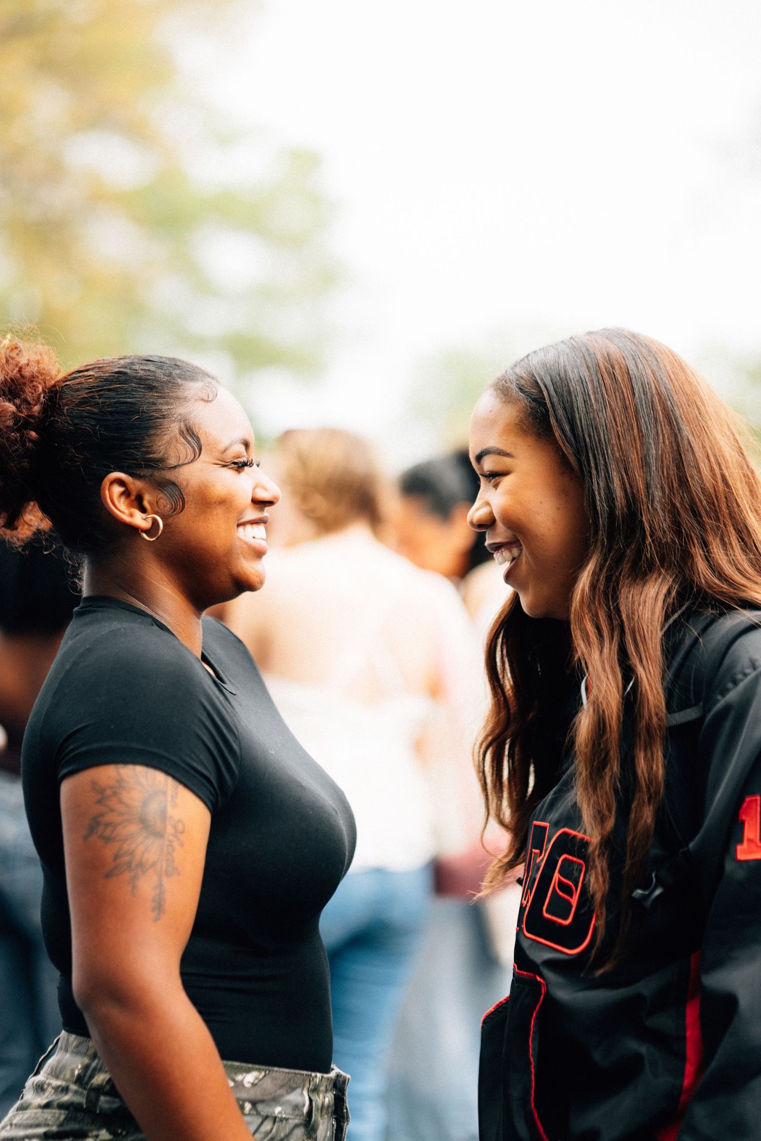 Two deltas share a joyful moment of laughter together while standing outdoors.
