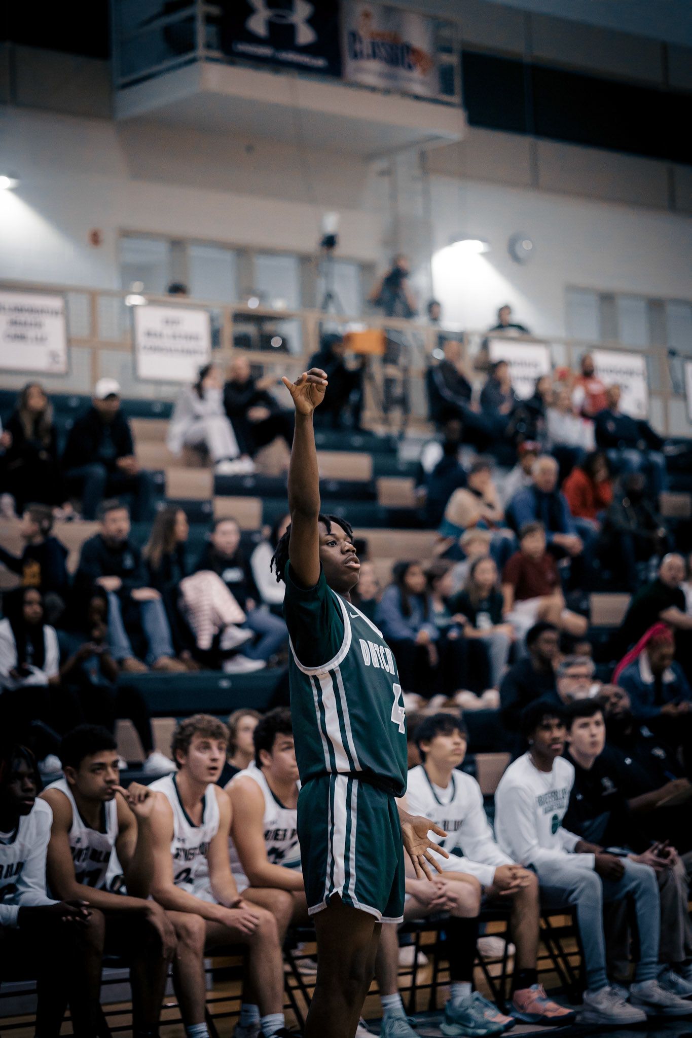 Basketball player takes free throw shot with crowd watching from sidelines.