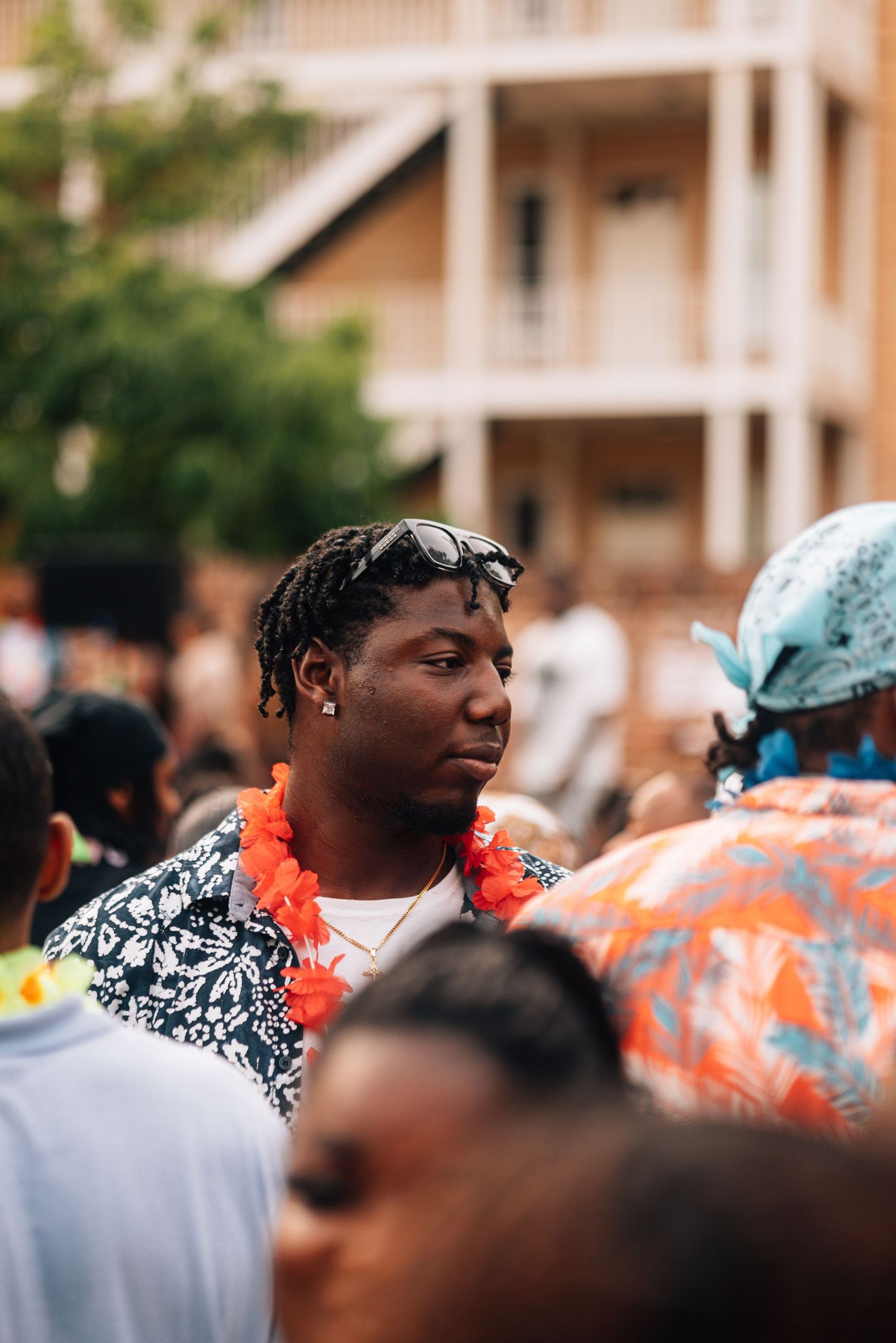 A person smiling and dancing at an outdoor event, wearing a black and white patterned shirt with orange accents.