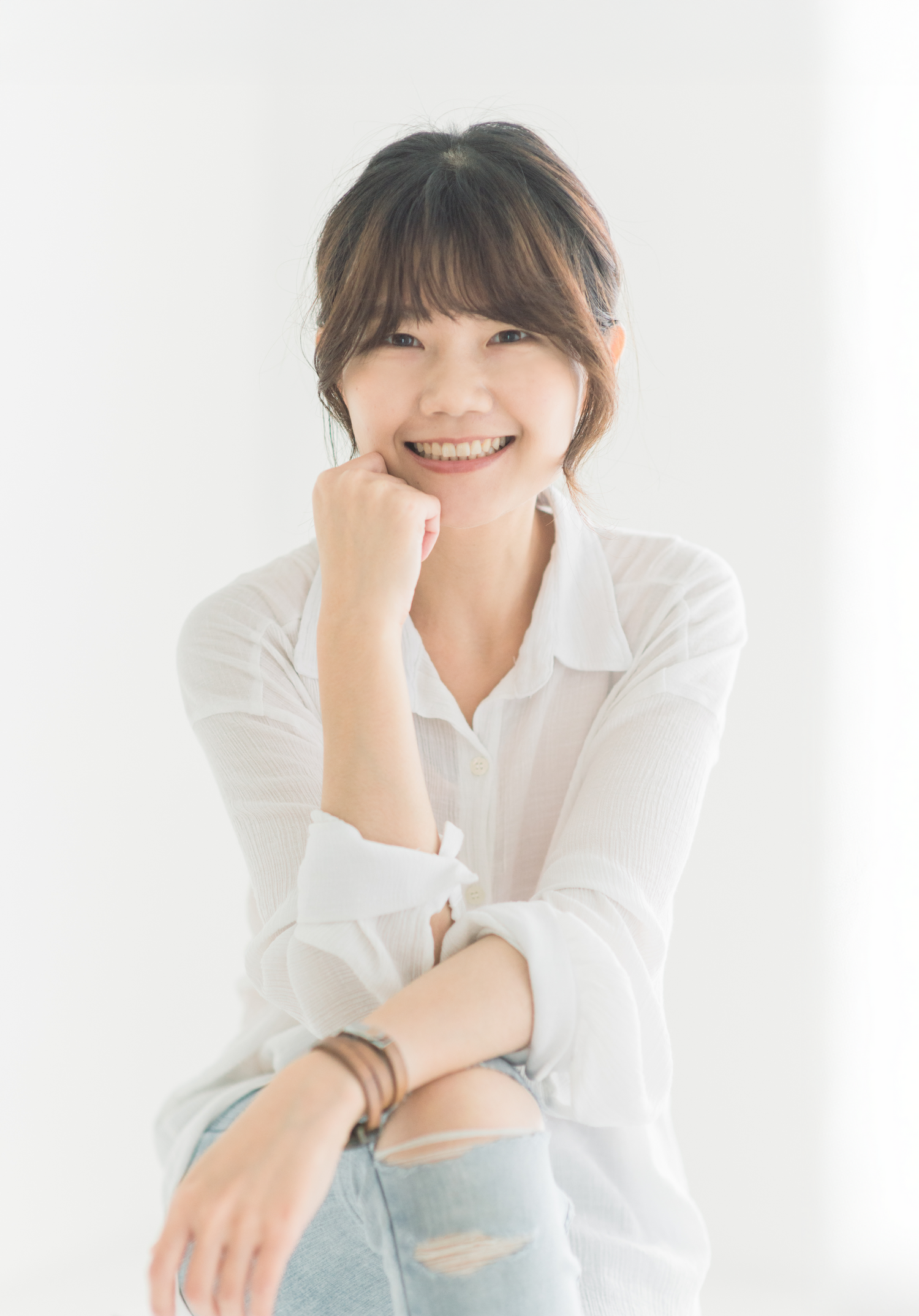Casual portrait of someone in a white button-down shirt and jeans against a light background.