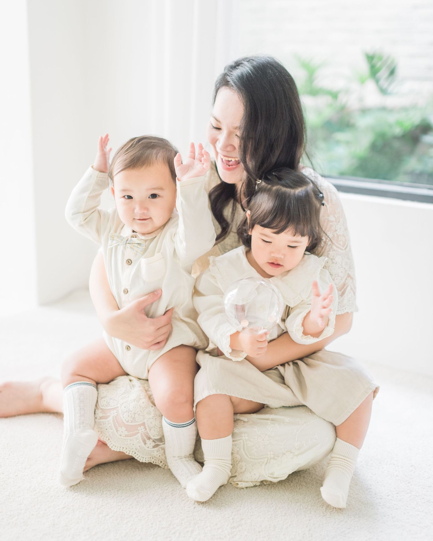 Bright indoor family portrait showing gentle moments of connection in matching light outfits.