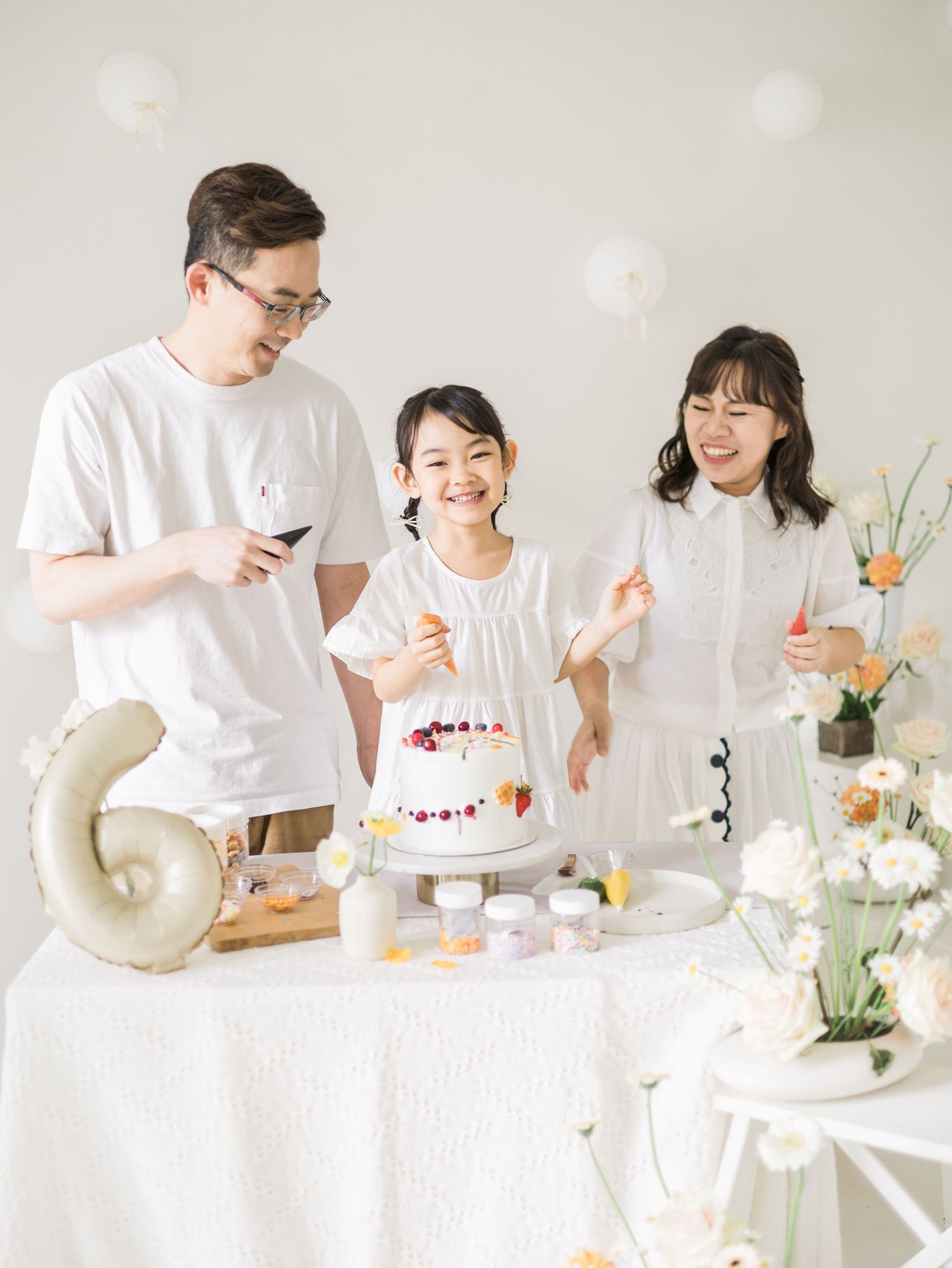 A joyful family celebration scene with a decorated cake and party decorations on a white table.