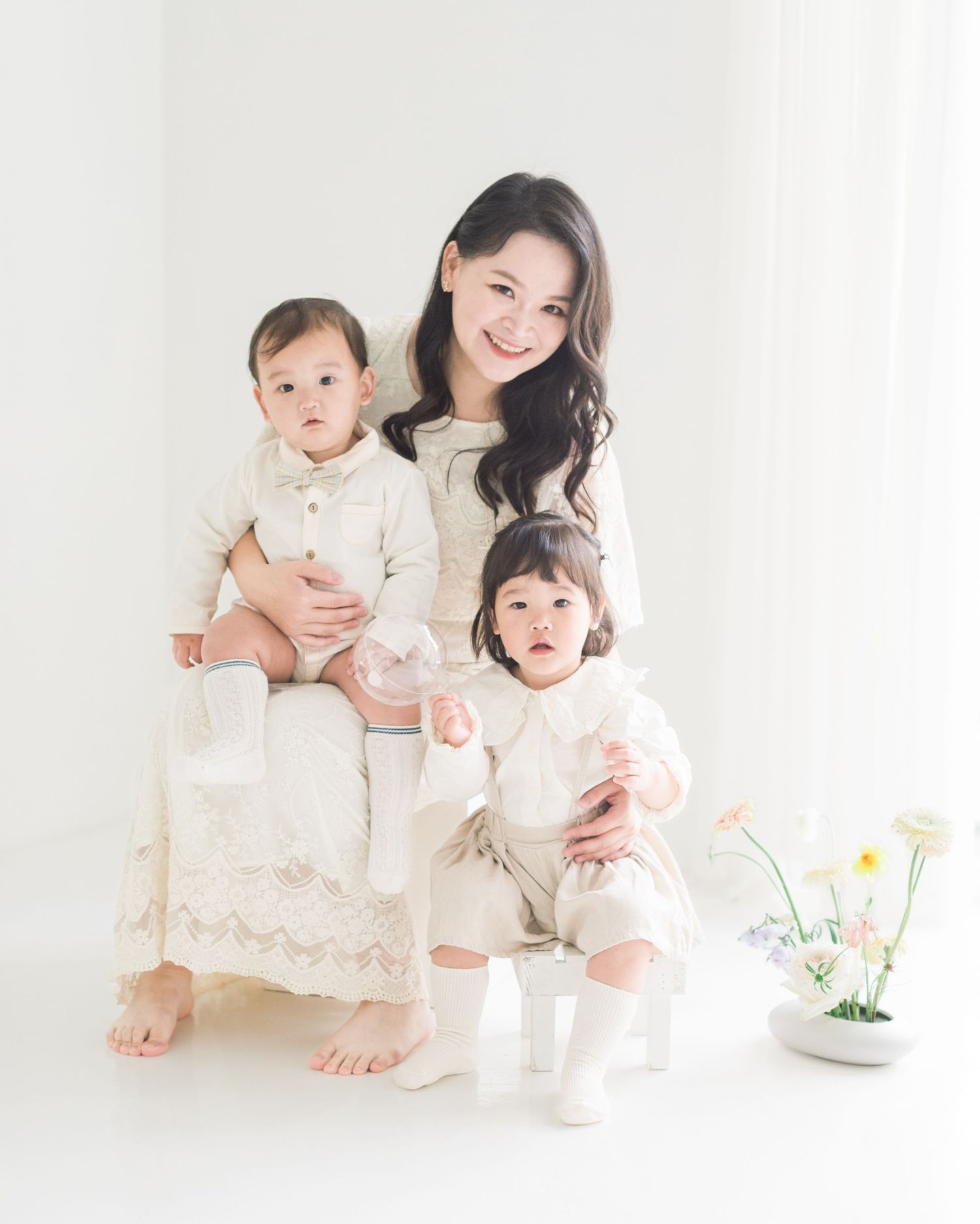 An intimate studio portrait in soft white tones with gentle natural lighting.