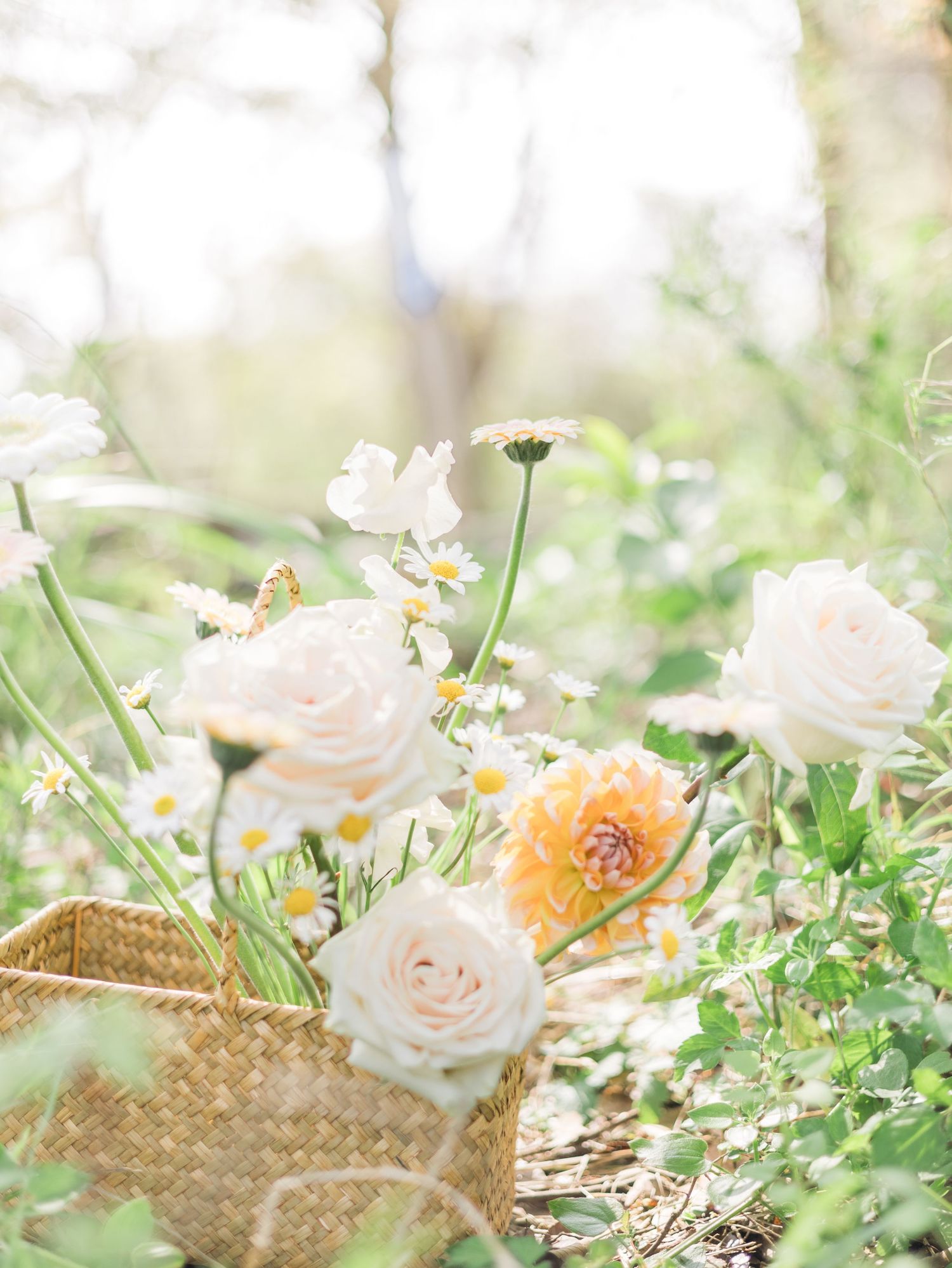 Delicate roses and wildflowers arranged in a woven basket with soft natural lighting.